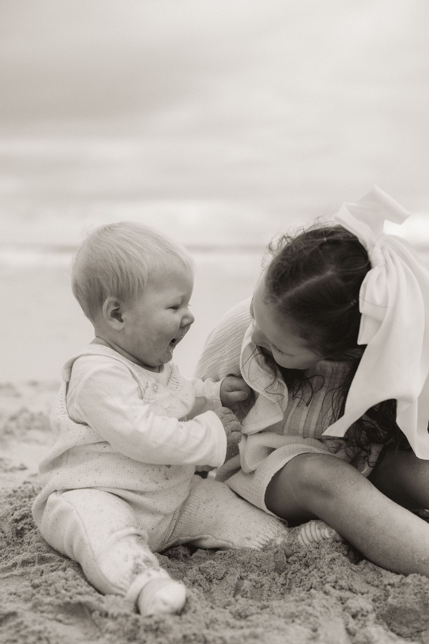 A heartwarming black and white moment between siblings on the beach.