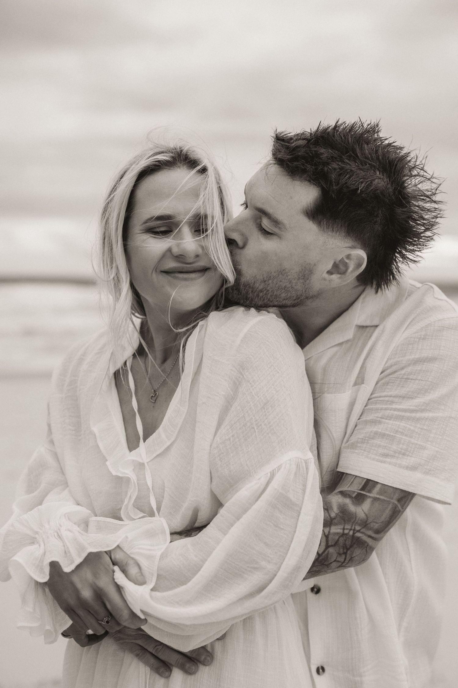 An intimate black and white portrait of a couple sharing a tender moment.