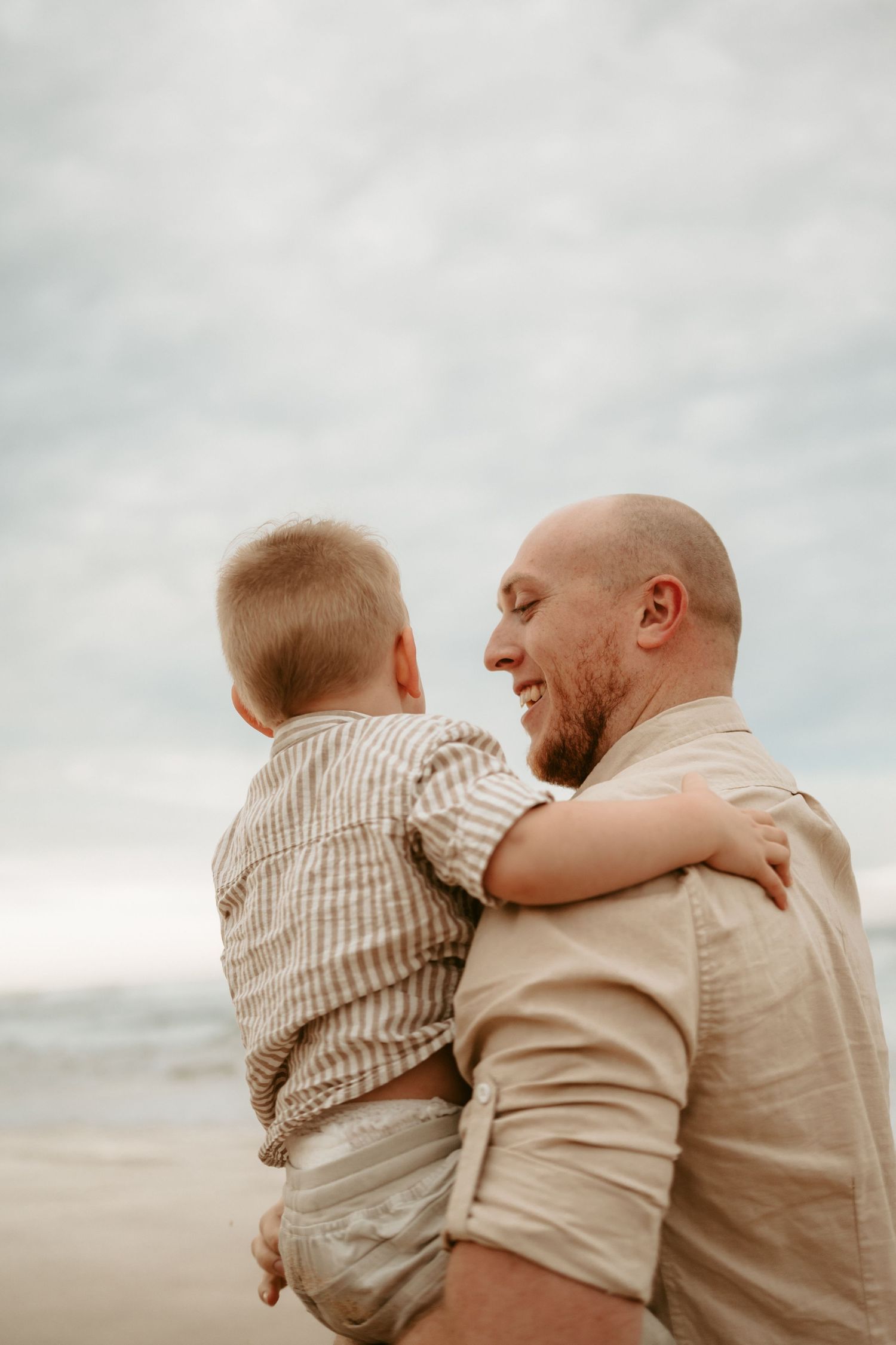 A tender moment between parent and child sitting together against an overcast sky.