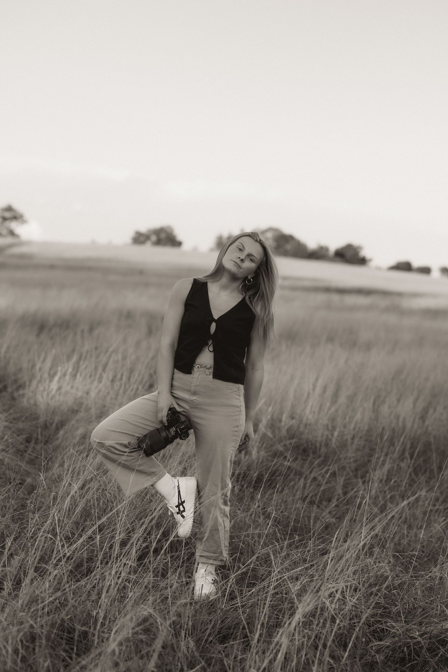 Black and white portrait series in a rustic field with dramatic poses and natural lighting.