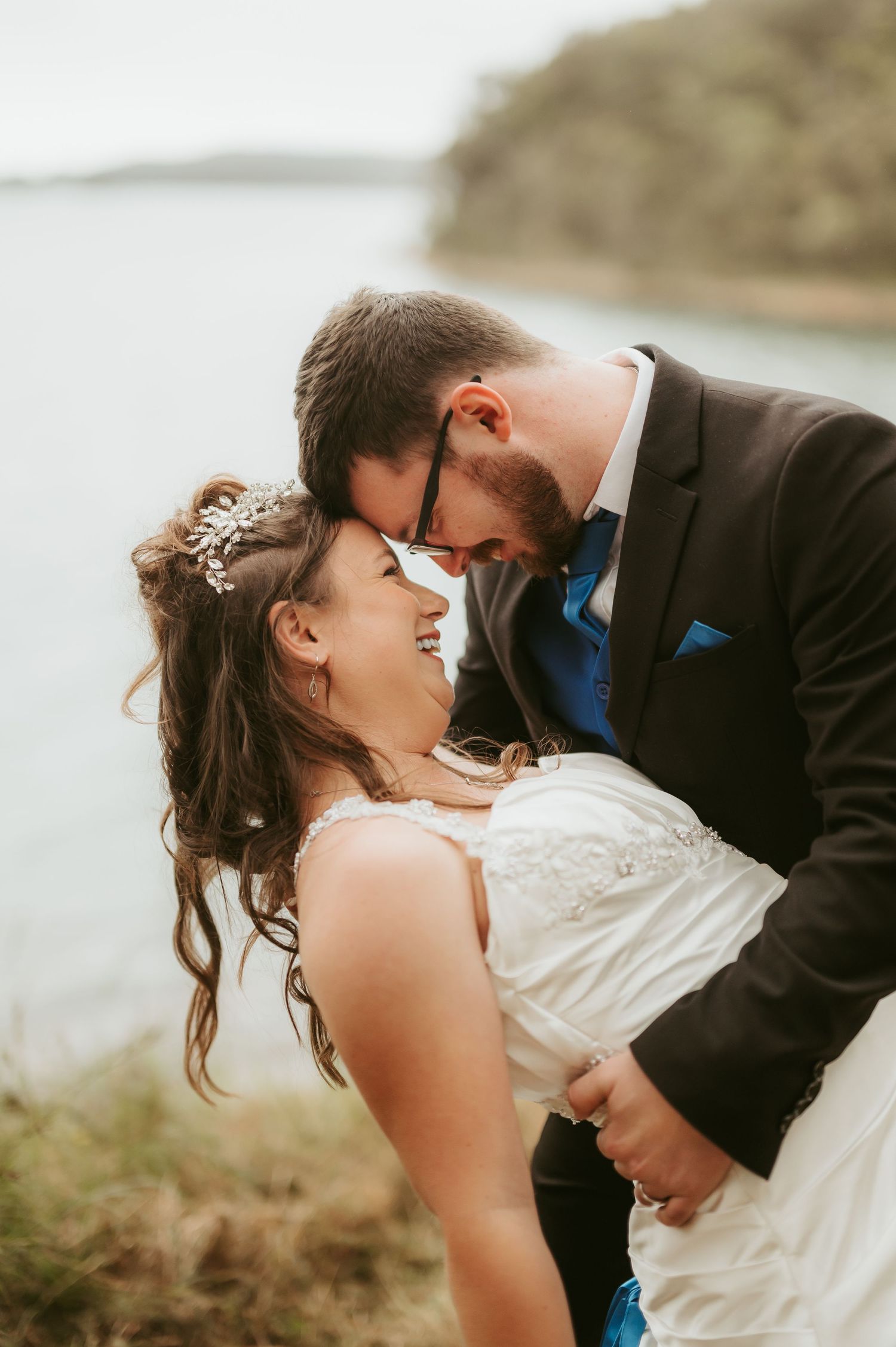 A romantic wedding couple shares intimate moments against a scenic coastal backdrop.