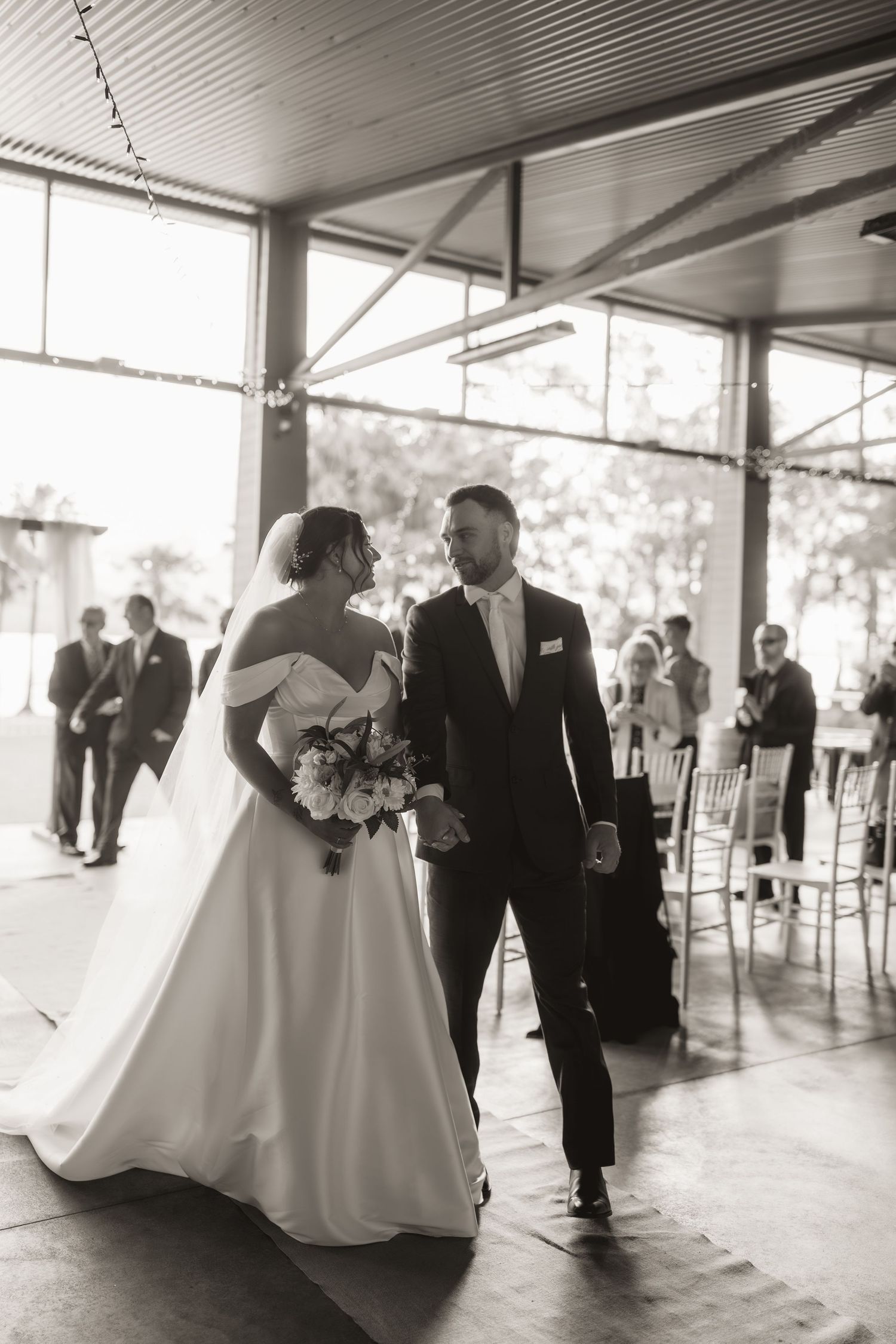 Black and white photo of wedding reception moments in a covered outdoor venue.