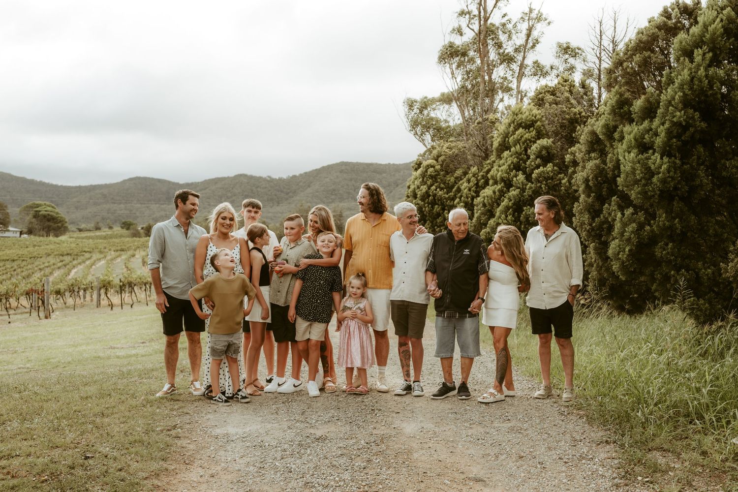 Group photo of people in coordinated outfits standing together in a vineyard landscape.