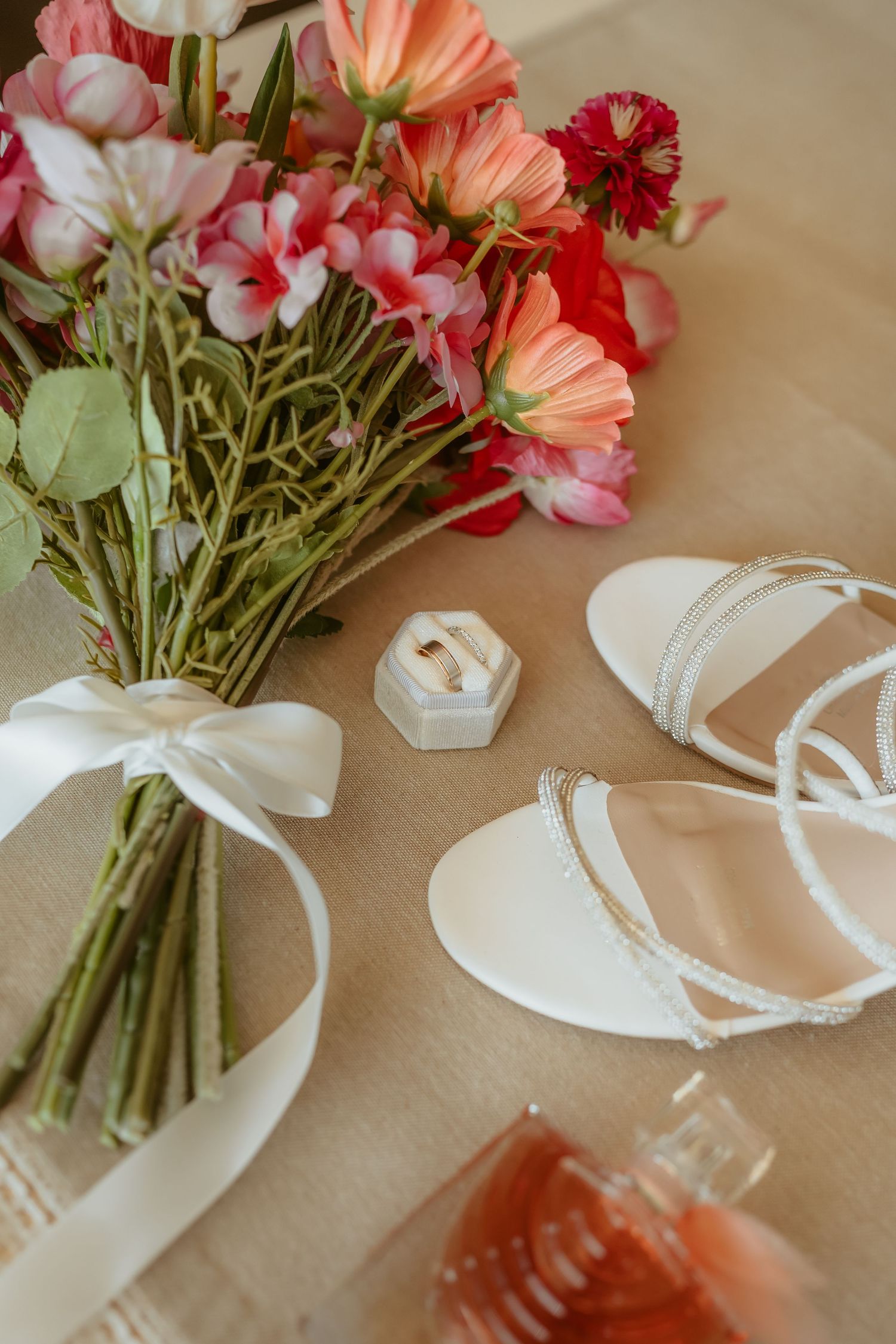 Pink and orange floral bouquets with white ribbons arranged on a beige surface.