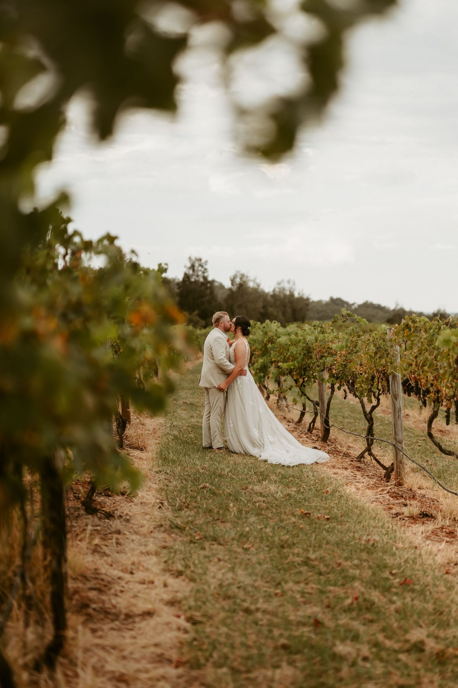Wedding couple photographed in vineyard with rolling hills in background.