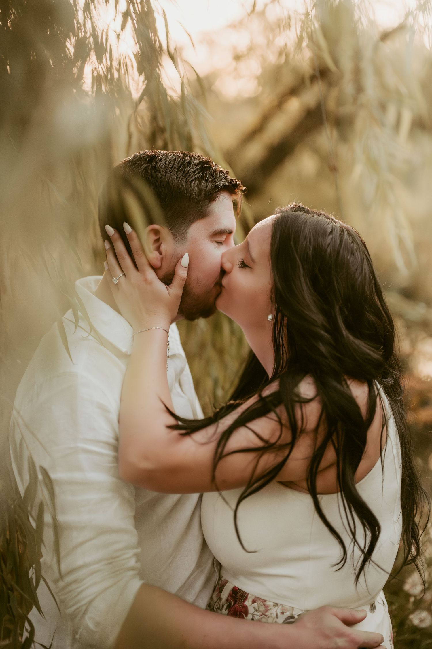 Romantic couple sharing intimate kisses in golden sunset light through trees.