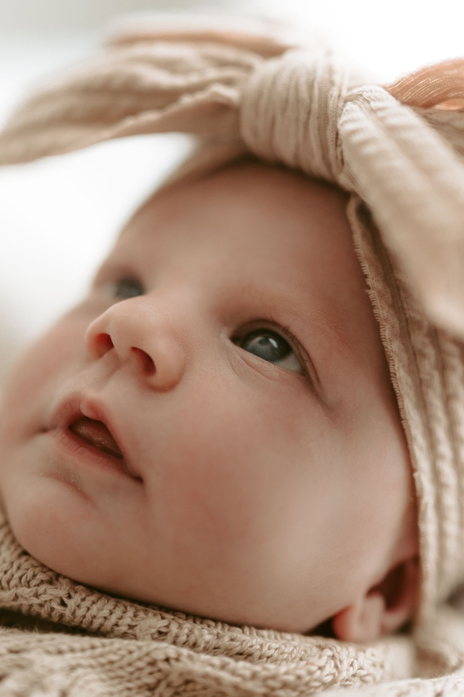 Gentle close-up of a sleeping newborn wrapped in soft knit fabric.