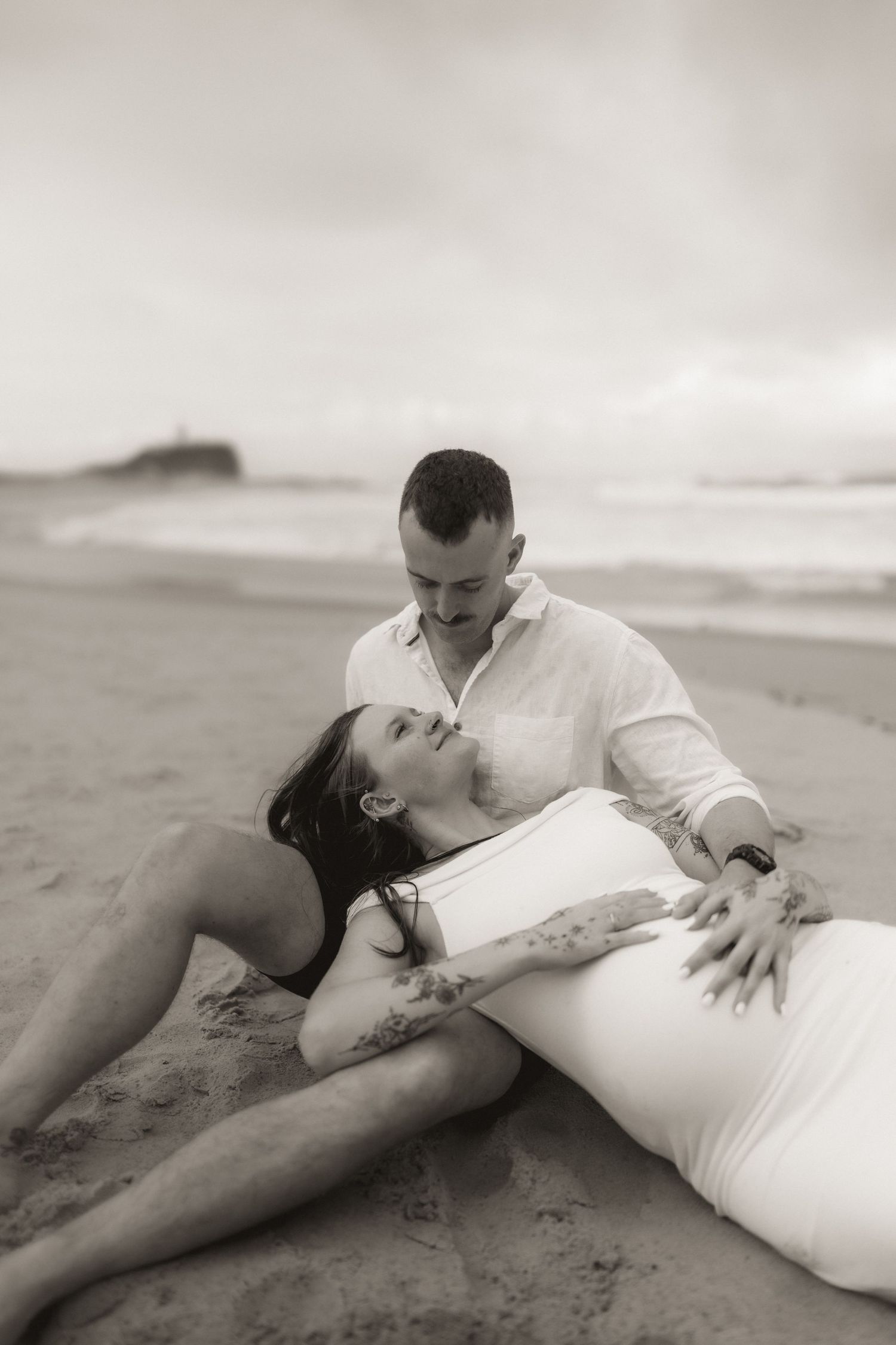 A romantic black and white photo sequence of a couple embracing on a sandy beach.