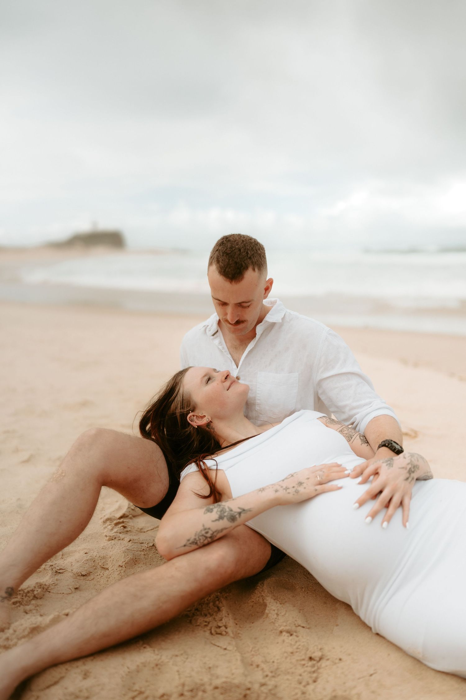 Romantic beachside maternity photos showing tender moments between couple.