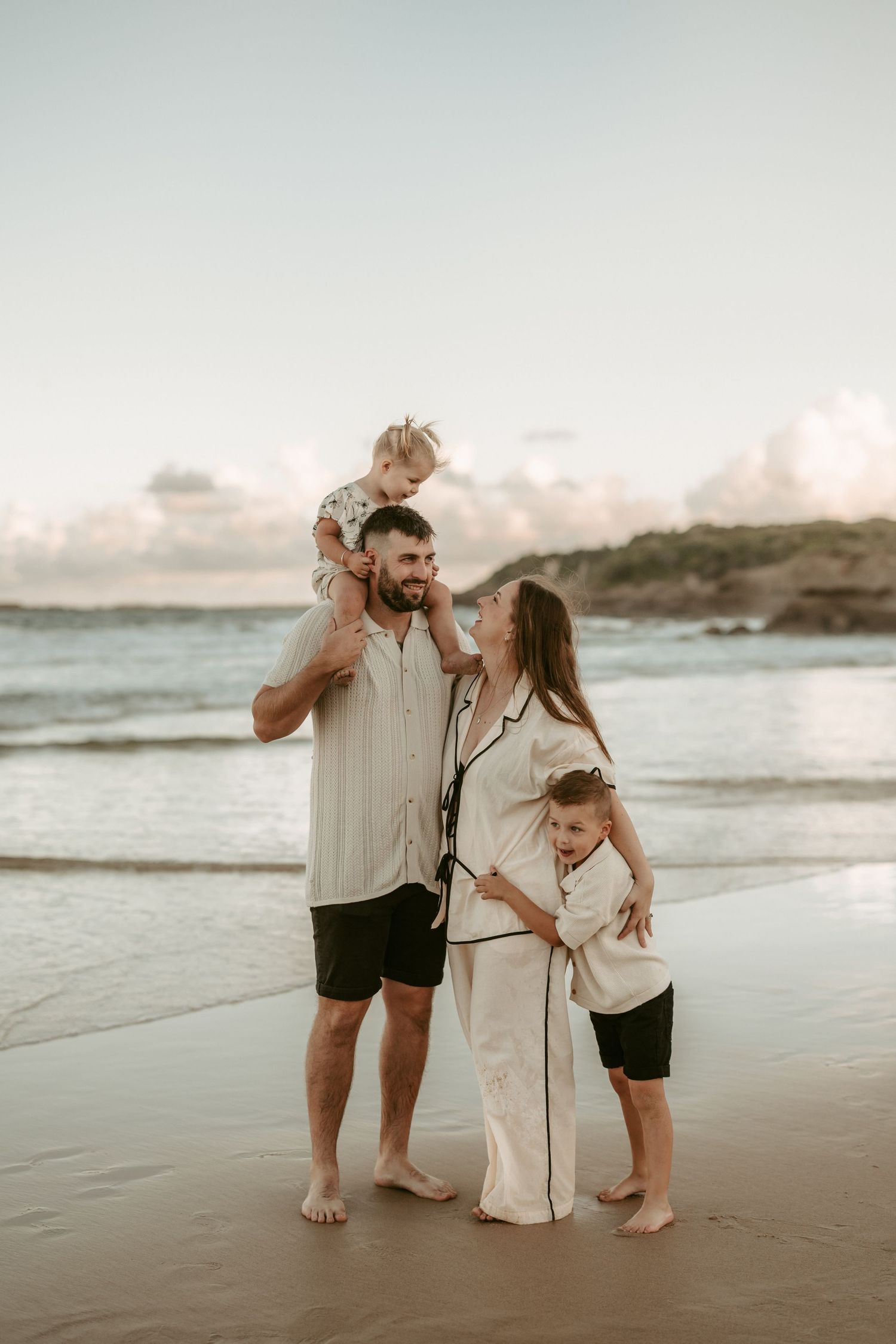 Family enjoying a sunset moment together on a peaceful beach shoreline.