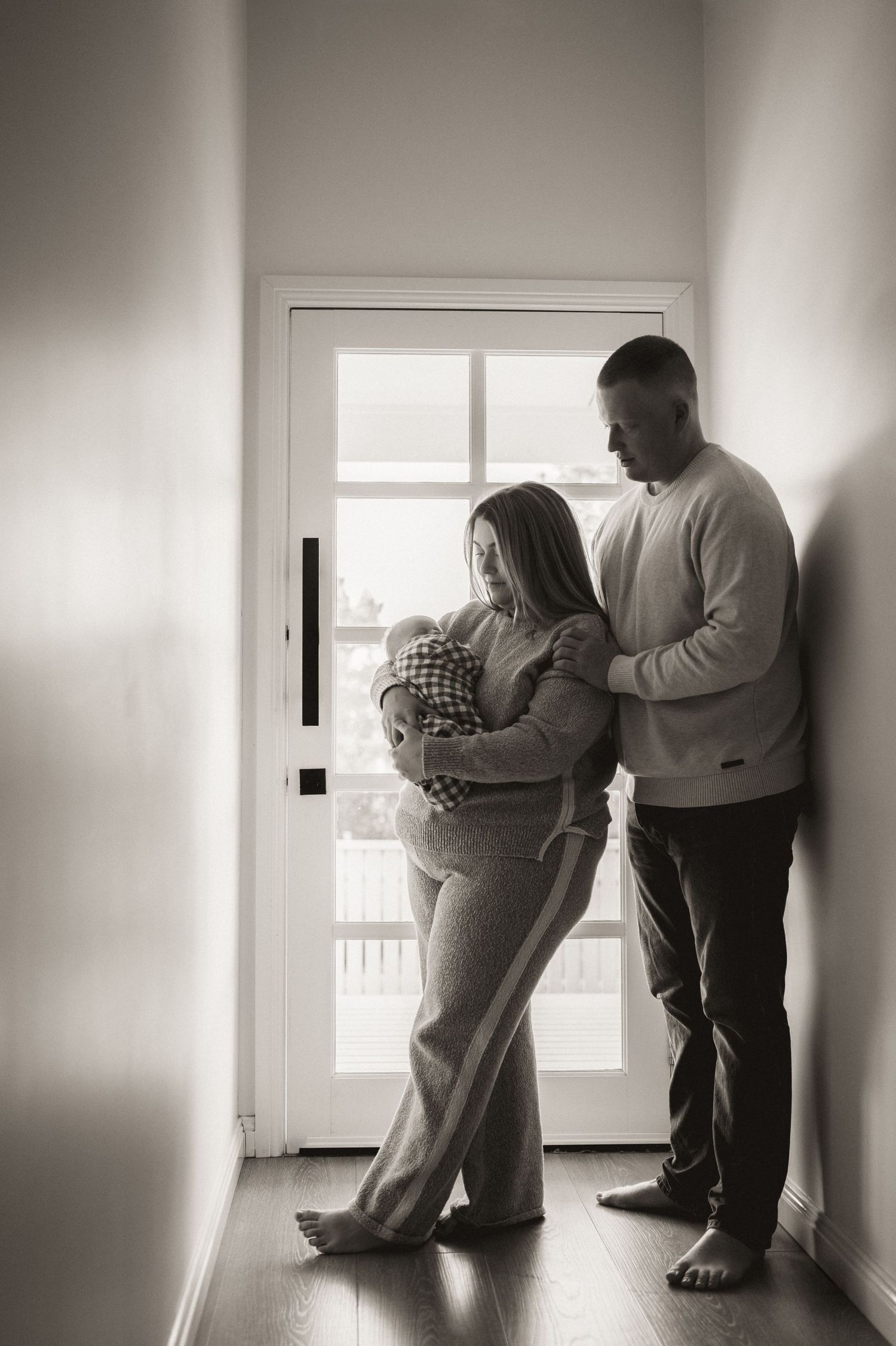Black and white series showing intimate family moments in a minimalist interior setting.