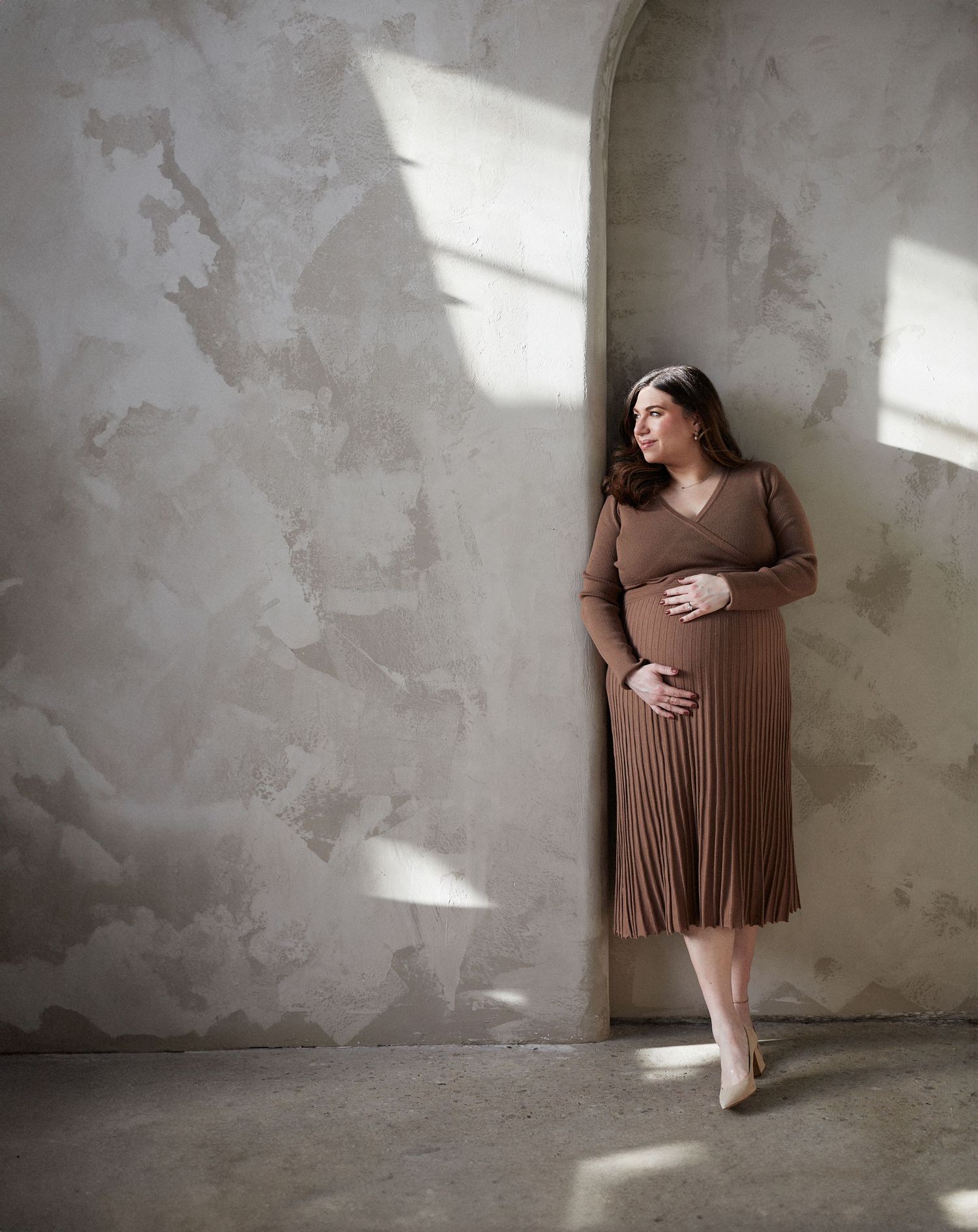Maternity photo of mother in sunlit studio.