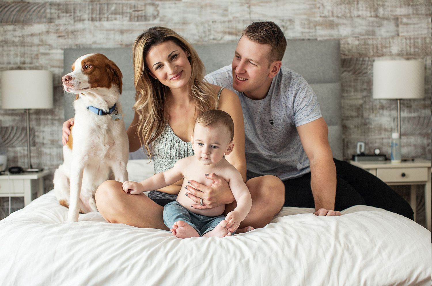Family posing on bed with dog.