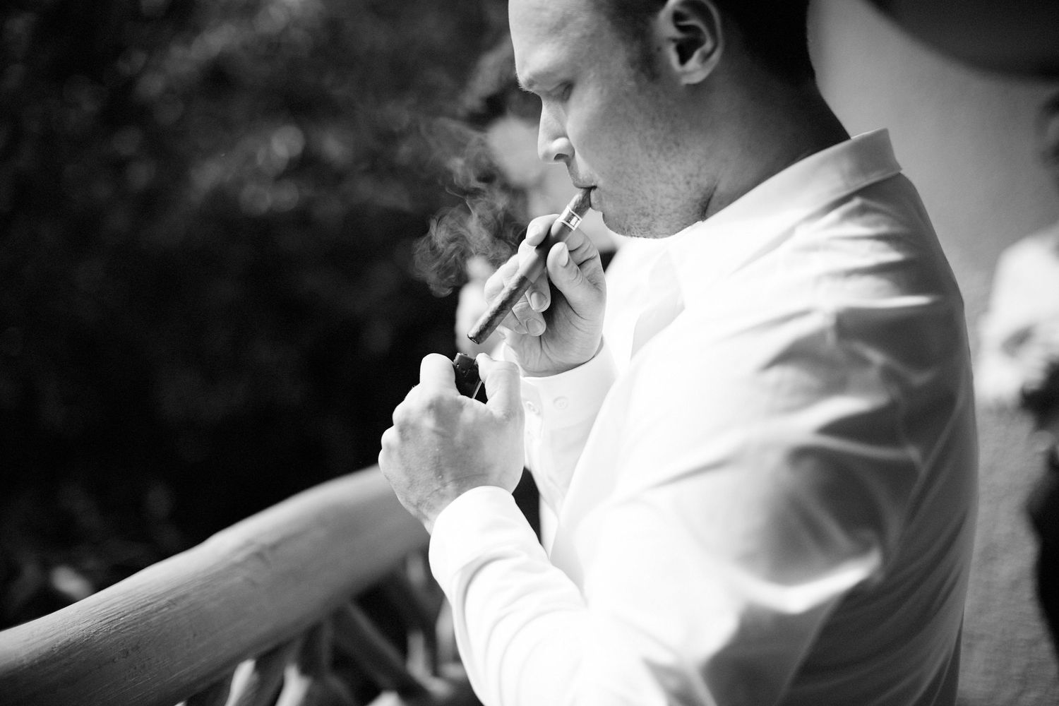 Groom and male wedding participants smoking cigars before ceremony.