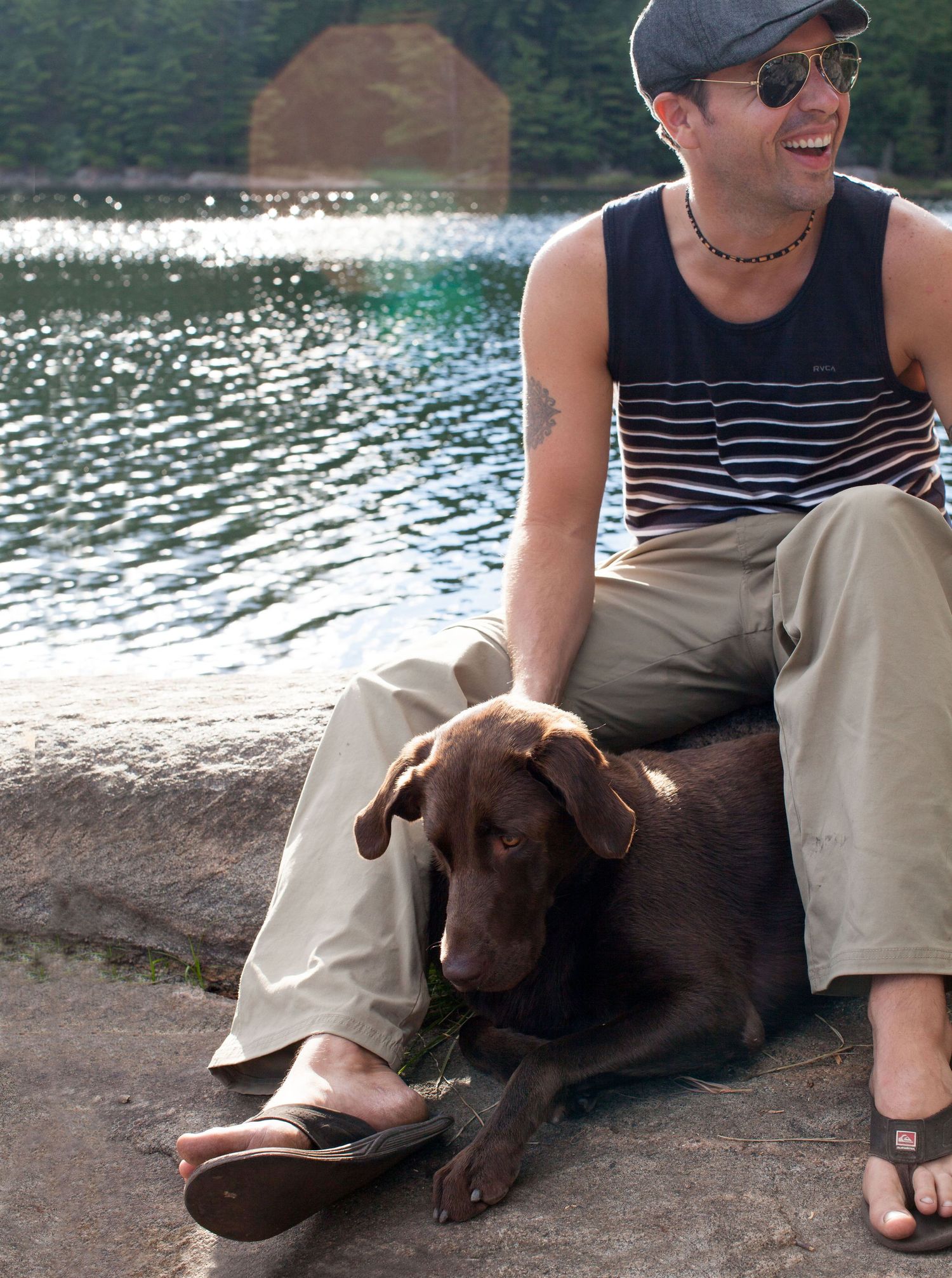 Photo of a man laughing with his chocolate lab.