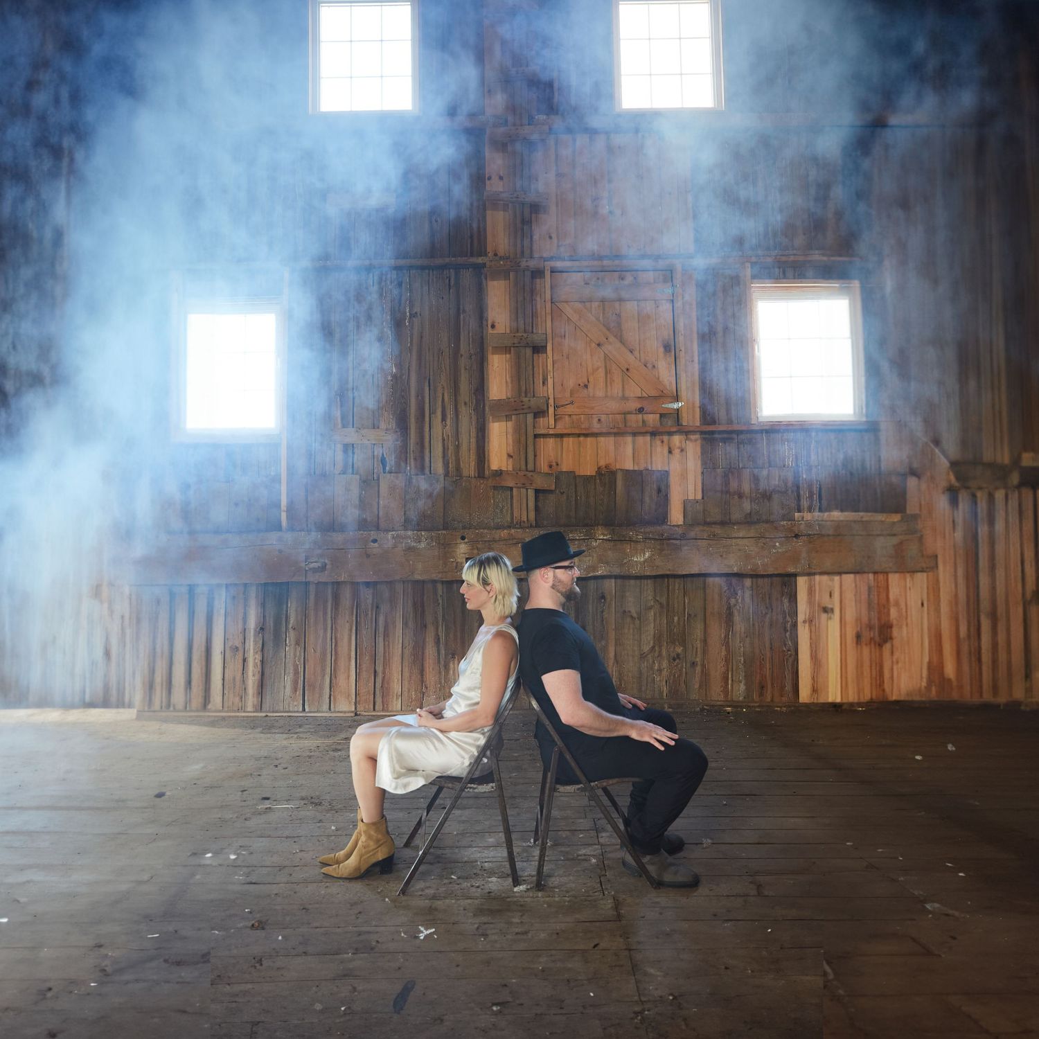 Band members back to back in a barn with atmospheric smoke to make it look edgy.