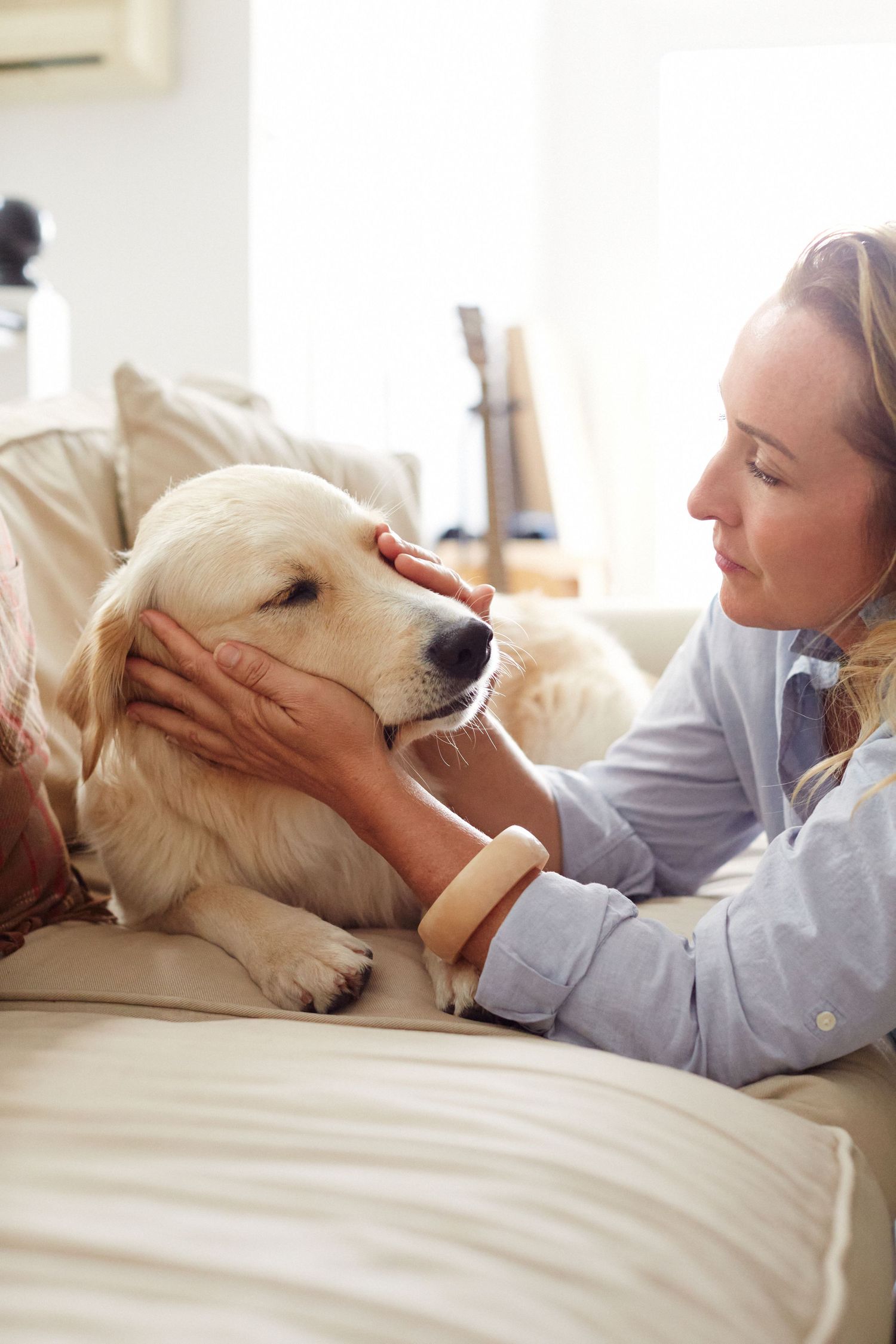 Photo of a woman caressing her dog's face in her hands.