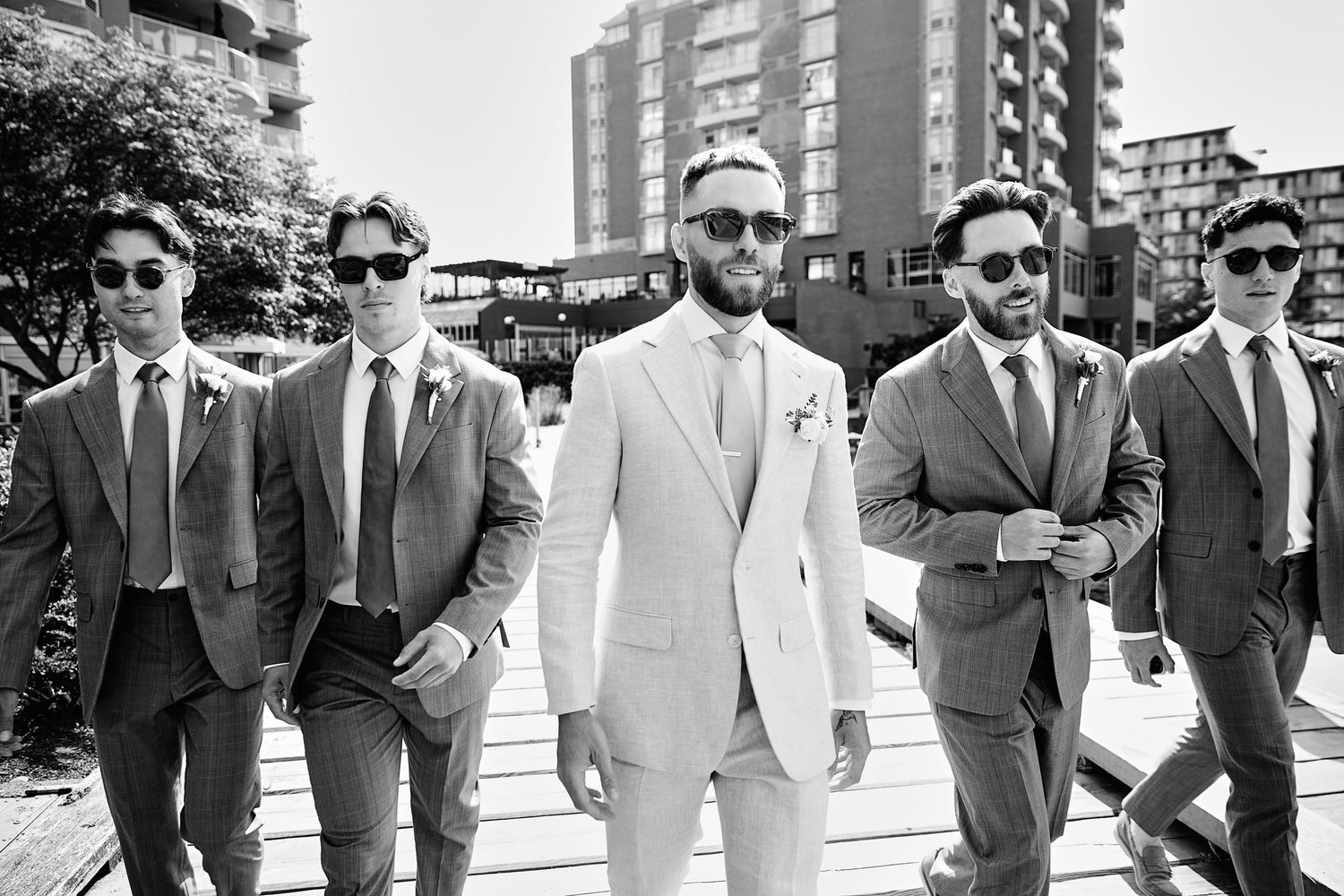 Wedding portrait of groom and groomsmen before ceremony, walking towards camera.