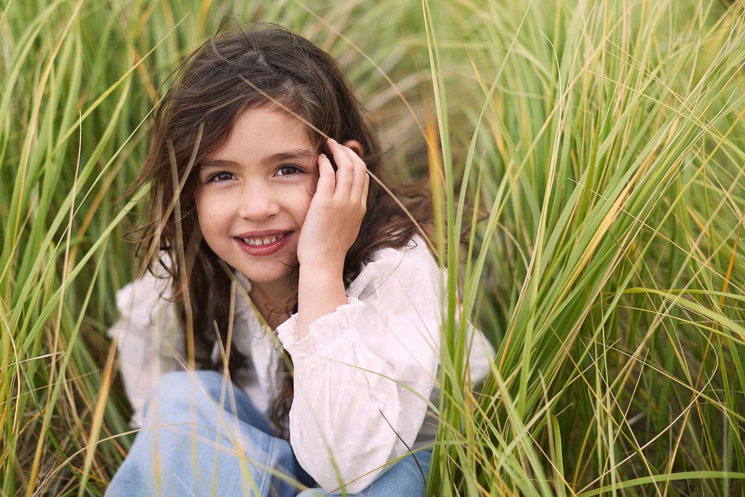 Photo of child sitting in tall grass.