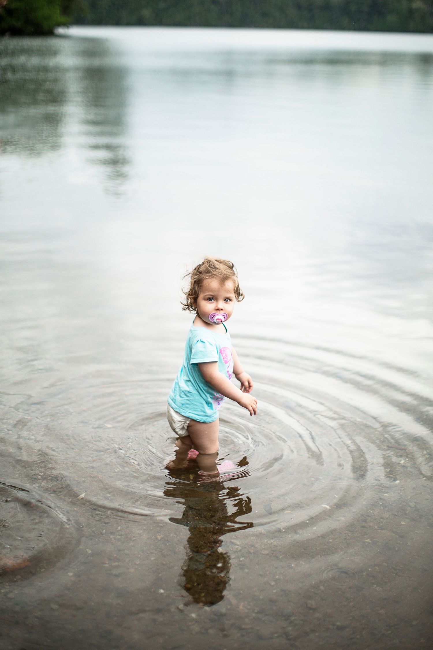 Small child walking into shallow lake.