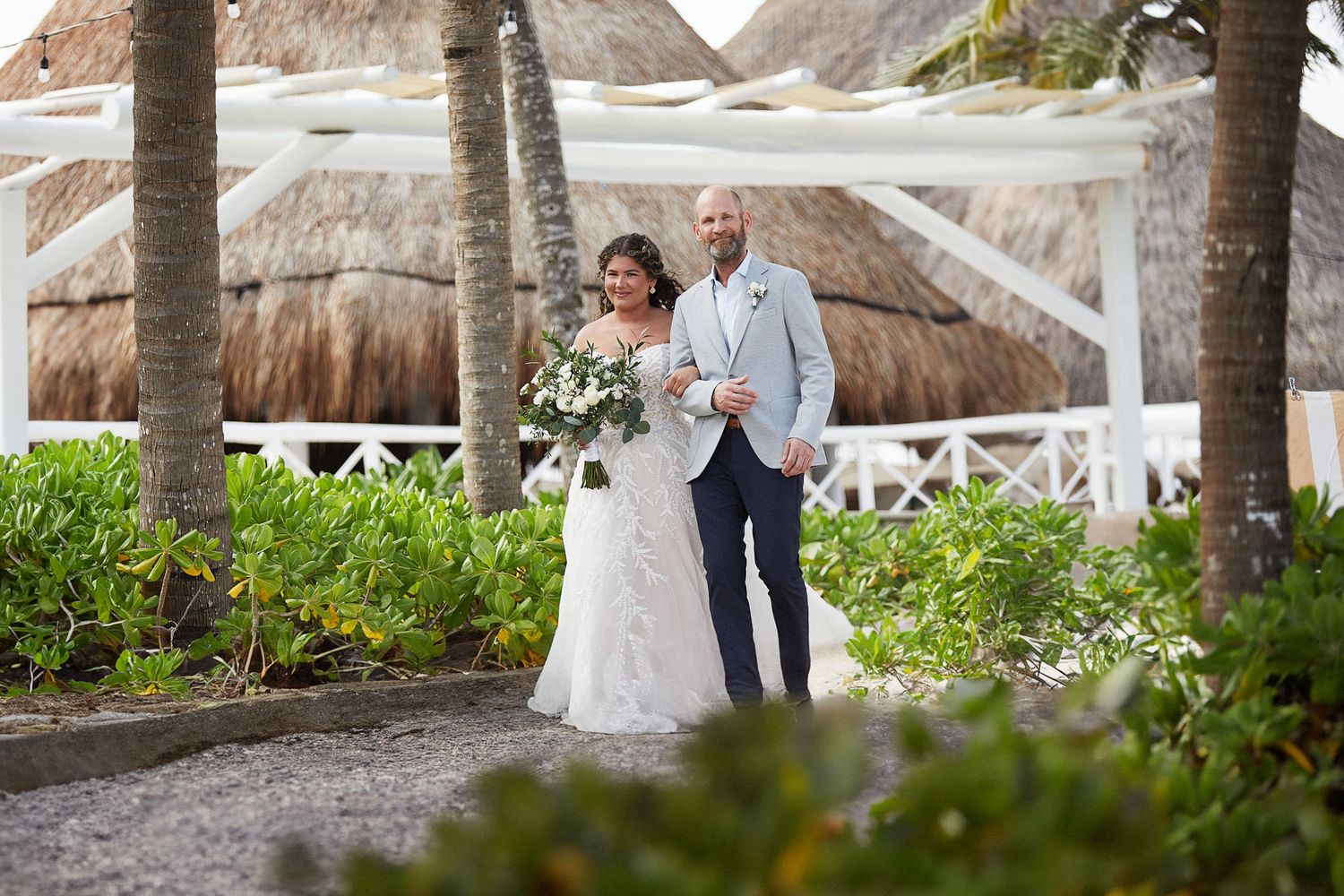 Bride and father of the bride walking down the aisle on the beach.