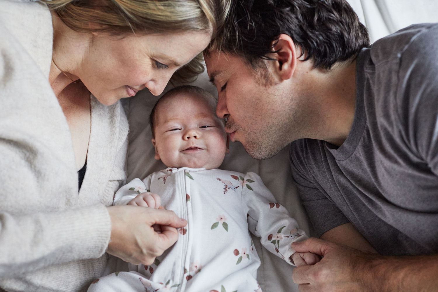 Mother and father kissing baby.