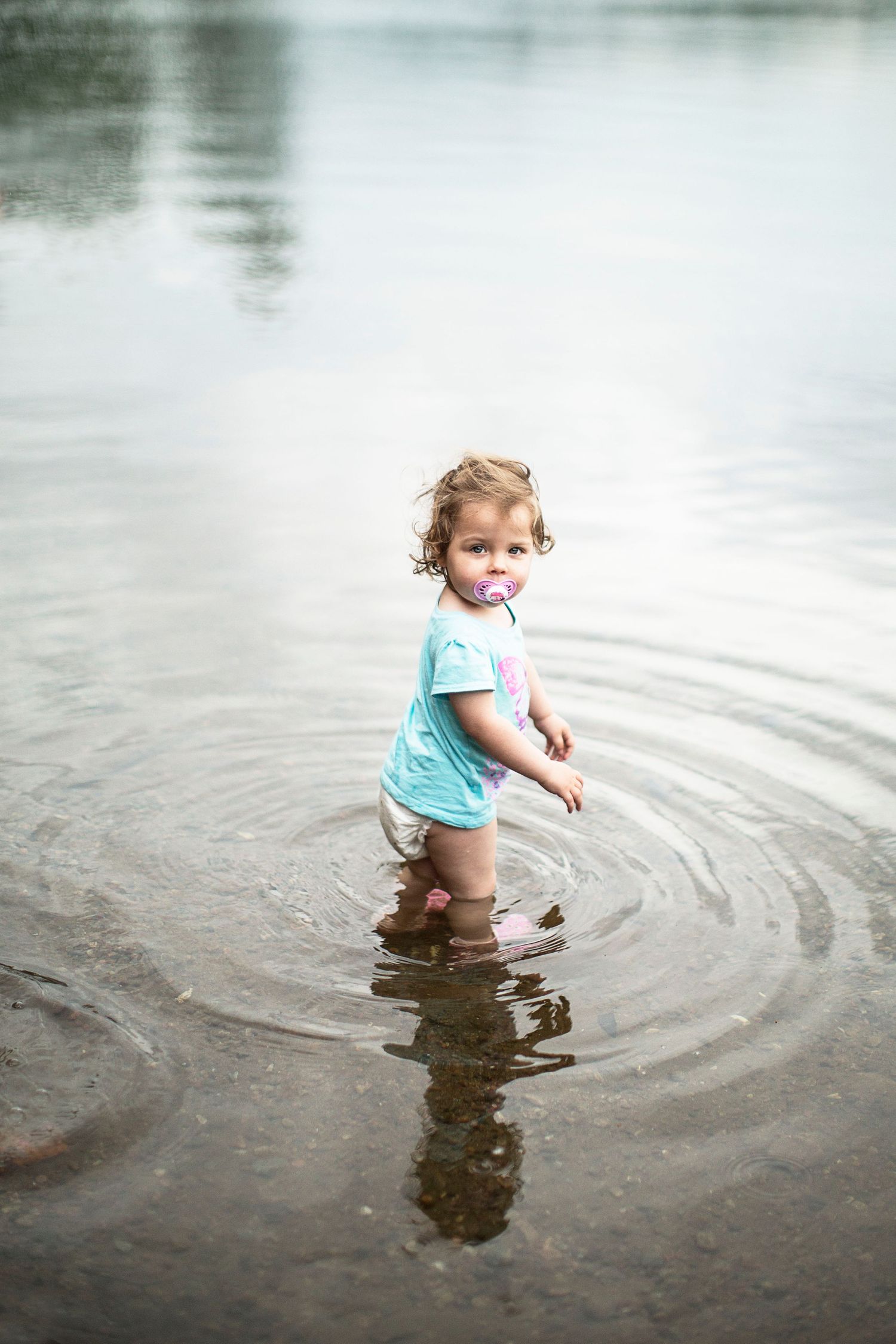 Baby walking into shallow lake.