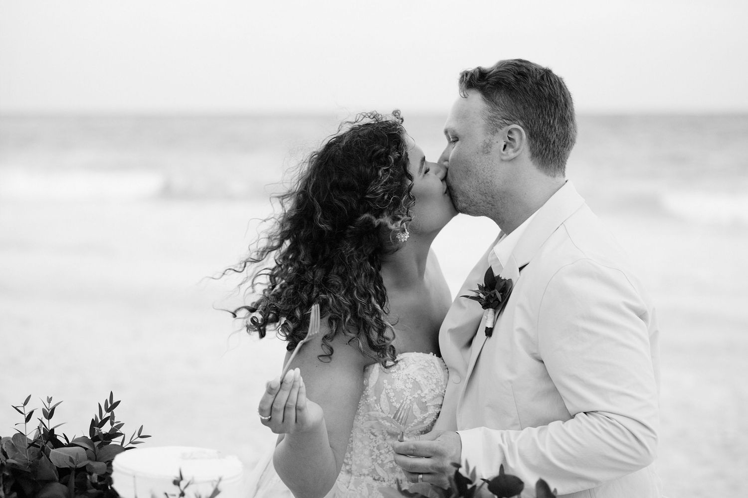 Bride and groom cutting cake and kissing.
