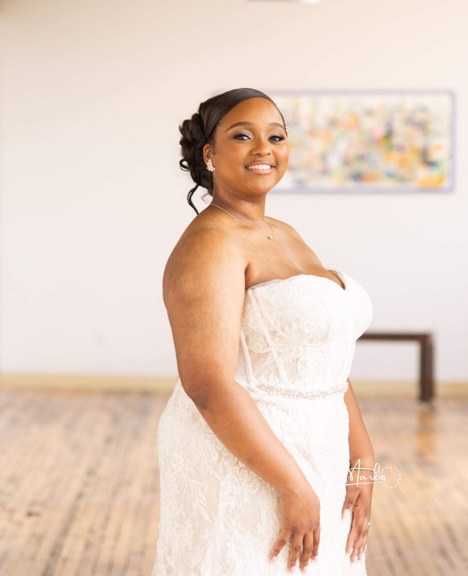 A bride in a white strapless wedding gown poses gracefully in a bright studio setting.