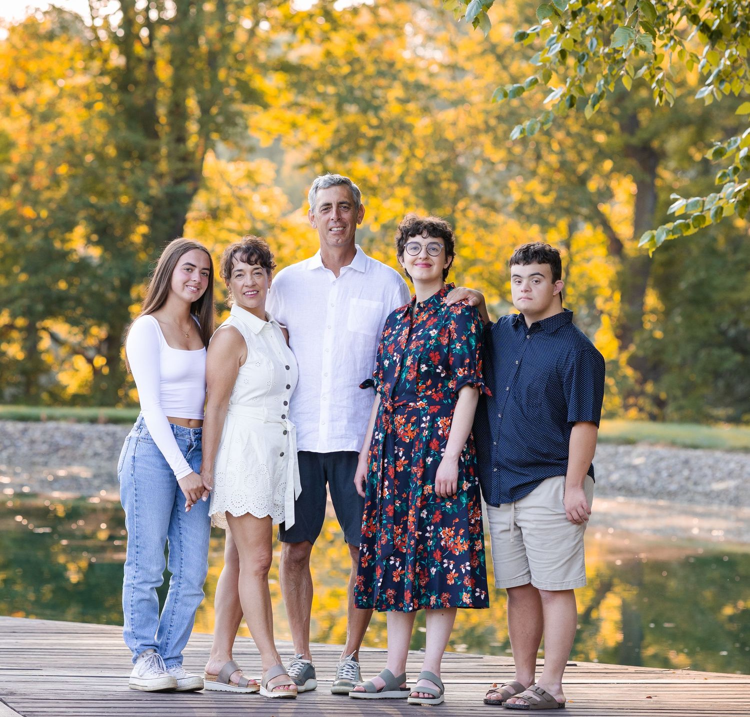 Family group sitting together on wooden deck during autumn photo session.