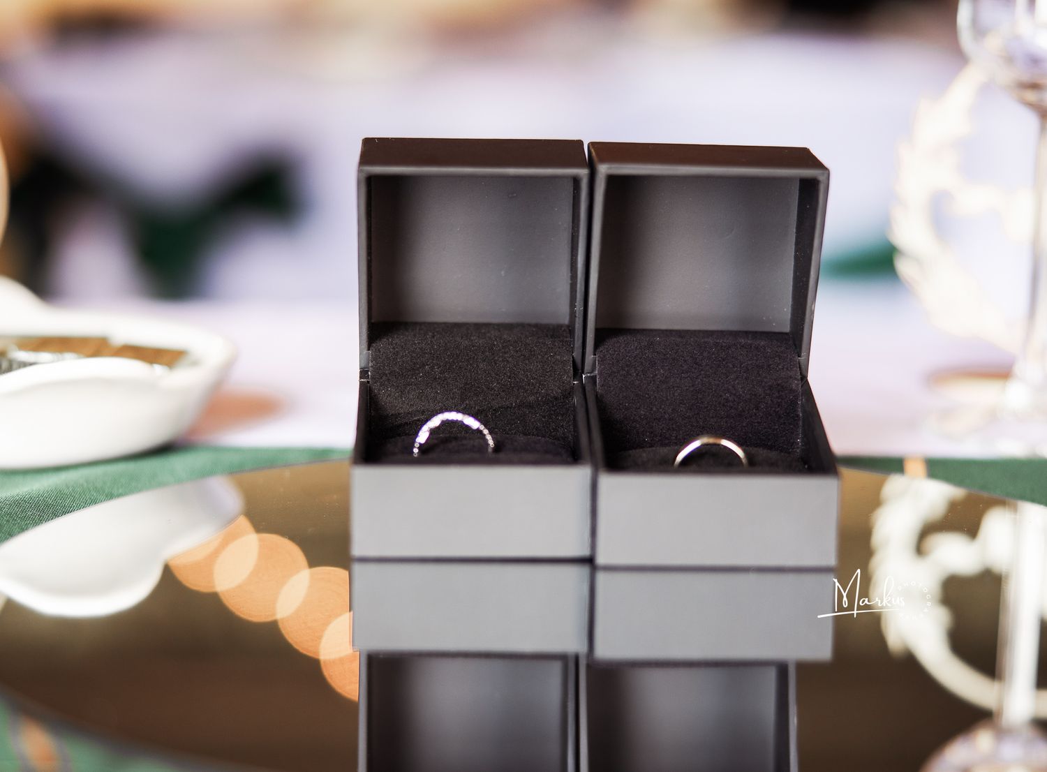 Black and silver wedding rings displayed on a dark surface with soft lighting and shallow depth of field.