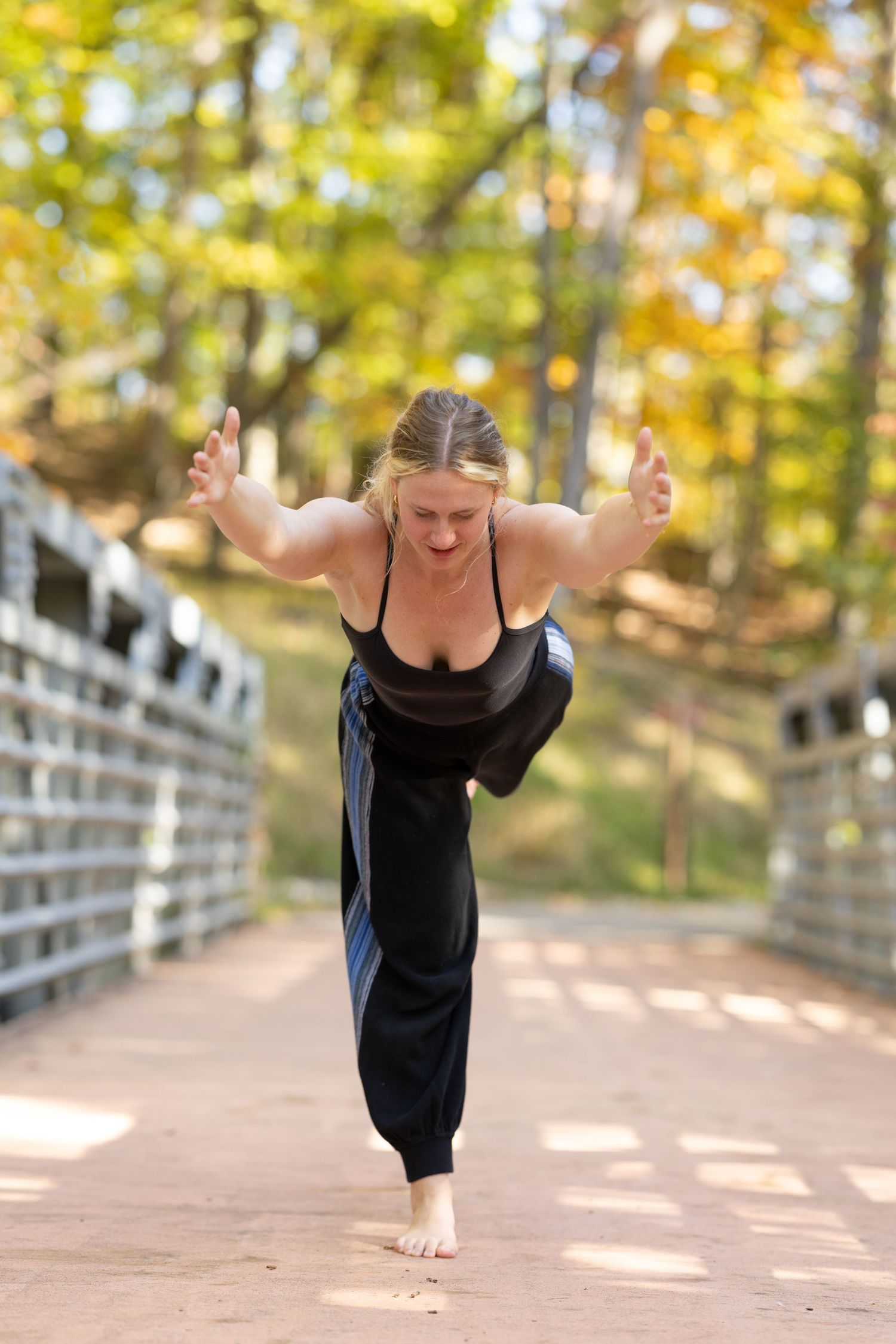 A sequence of four photos showing a dancer in a black dress performing graceful movements on a sunlit path.
