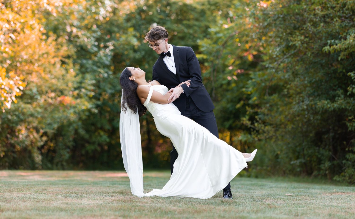 Romantic wedding couple poses in a series of dramatic dips against a natural outdoor backdrop.