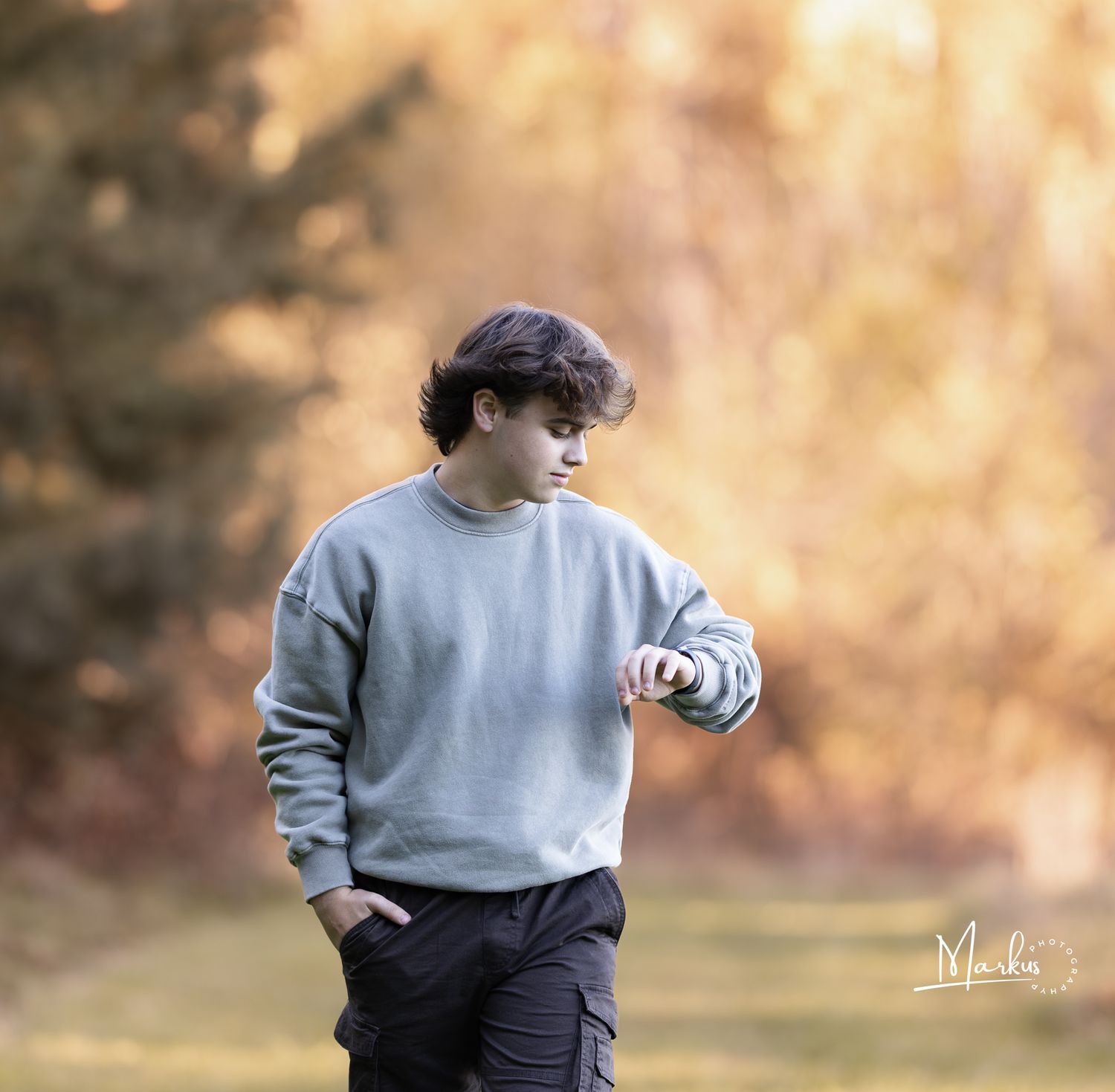 Young person in gray sweatshirt kicking soccer ball in outdoor field during autumn season.
