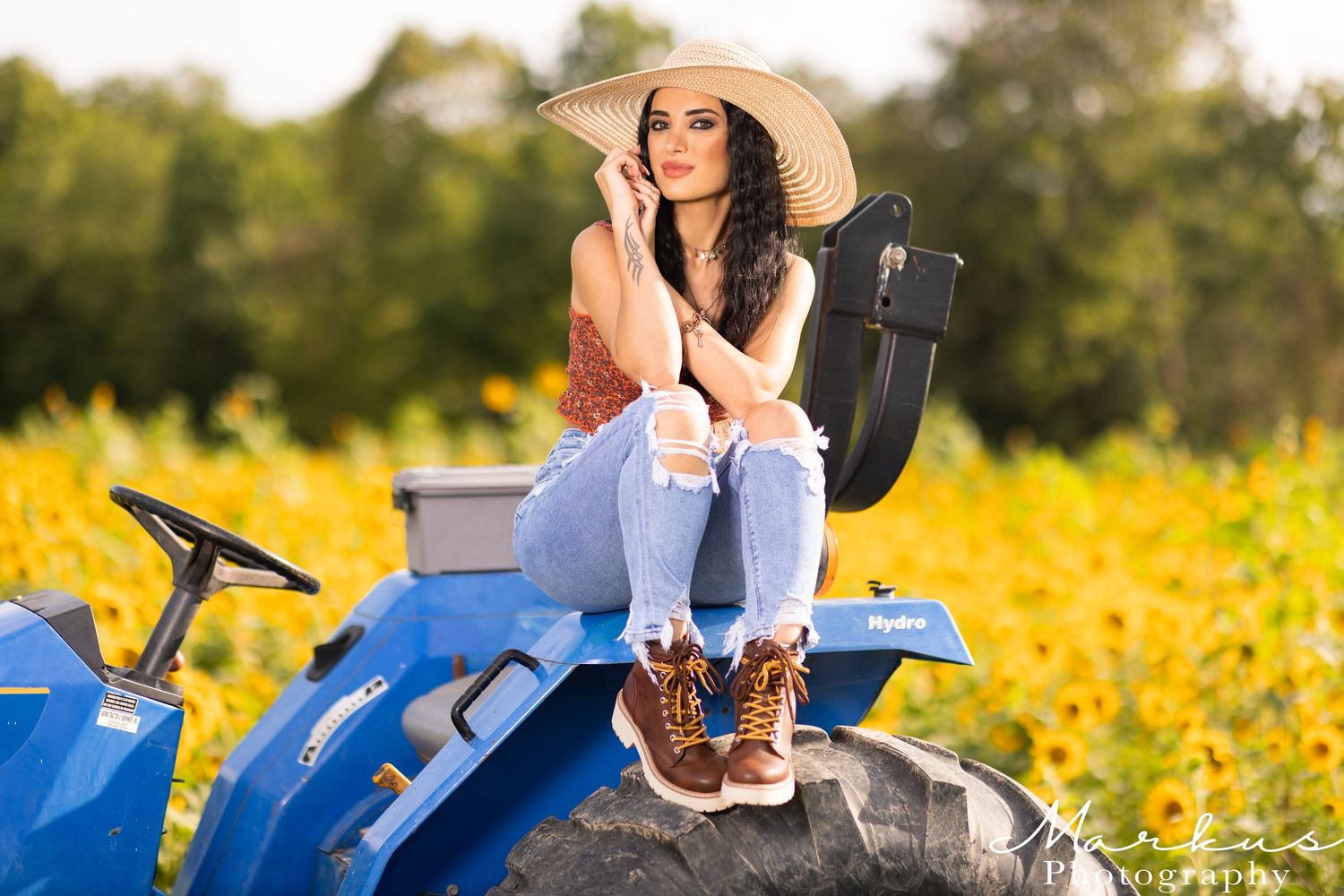 A person sits on a blue motorcycle in a field of vibrant yellow wildflowers during golden hour.