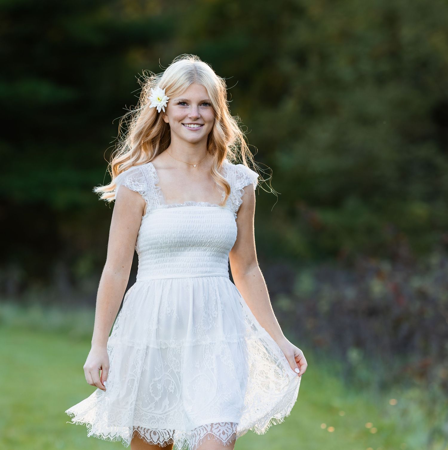 Outdoor photography in white lace dress on grassy field.