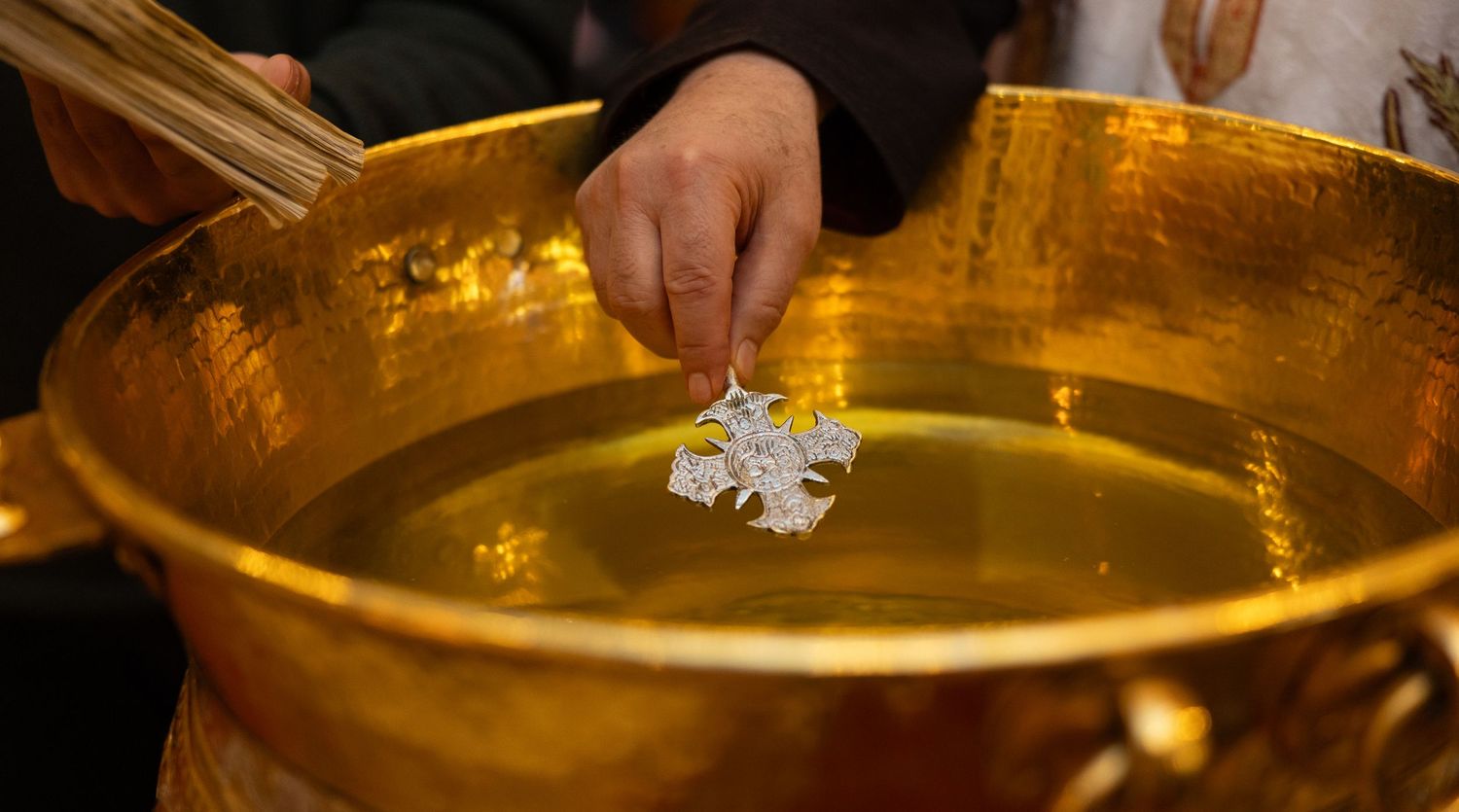 Hand using chopsticks to dip food into a large golden bowl filled with broth.
