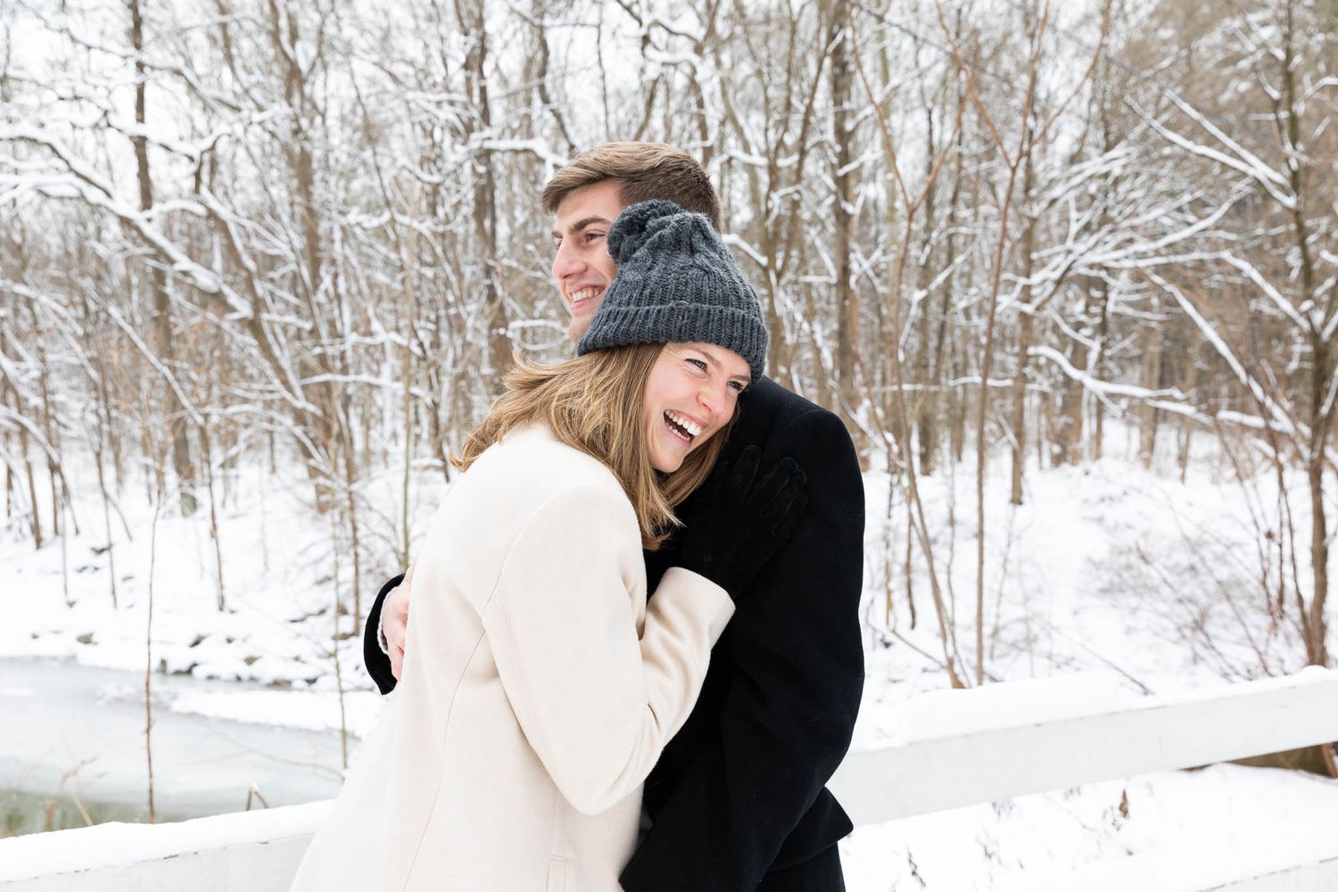 A couple shares a romantic moment in a snowy winter forest setting during a photo session.