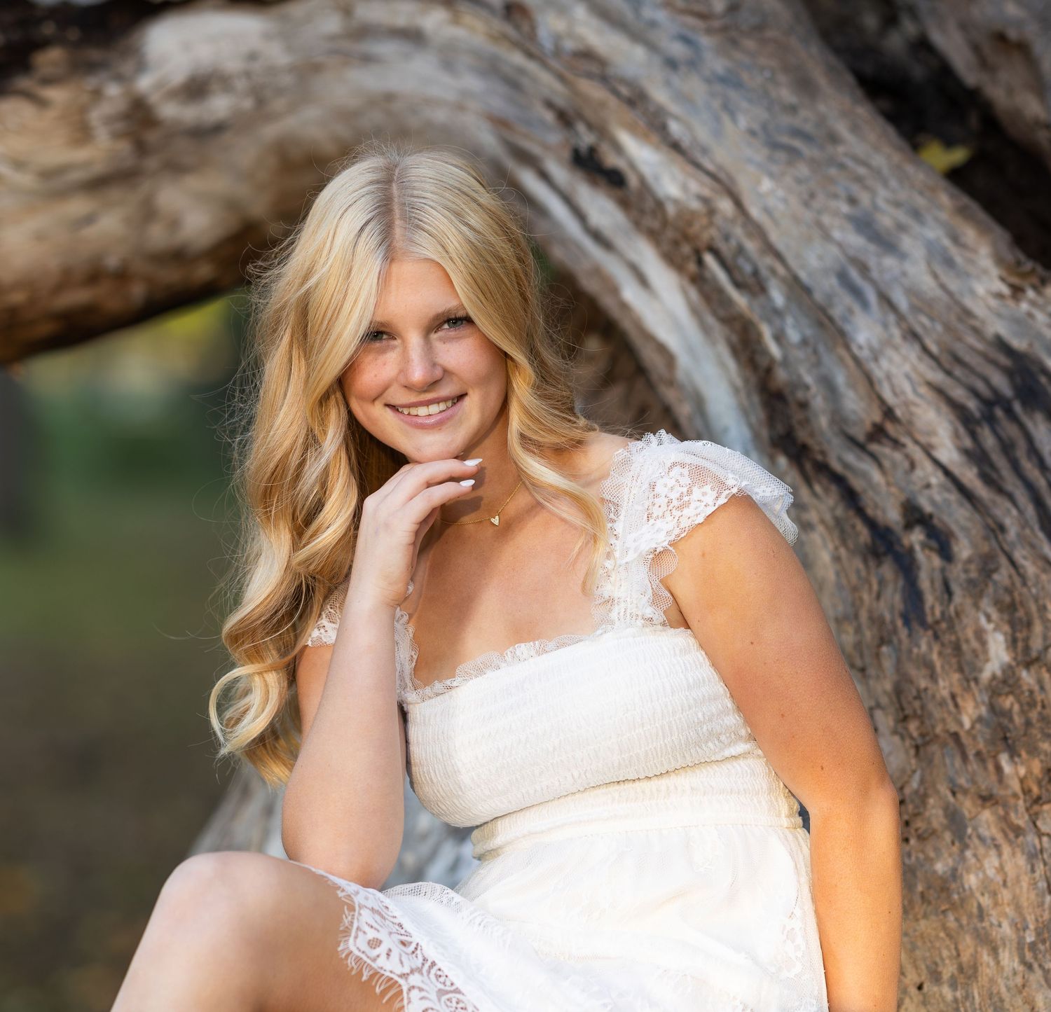 A bride in a white lace dress poses gracefully against a rustic wooden backdrop.