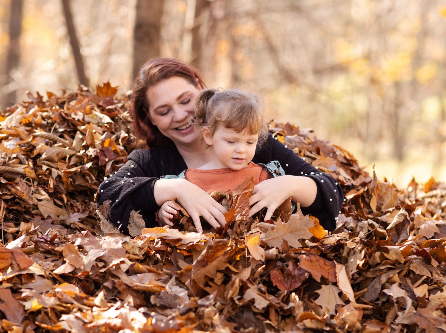 A joyful moment in a pile of autumn leaves as two people play together in the crisp fall foliage.