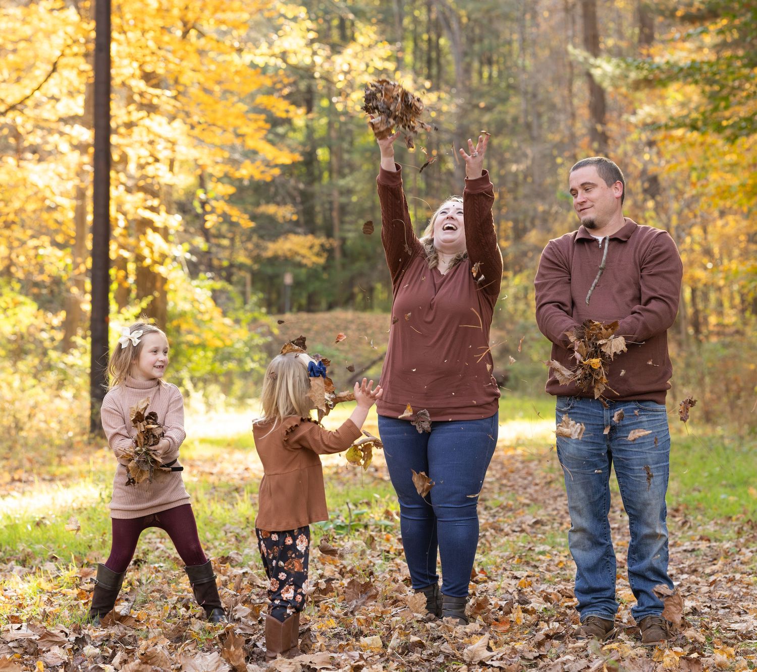 A series of autumn family photos showing people playing with fallen leaves in a wooded area with golden foliage.