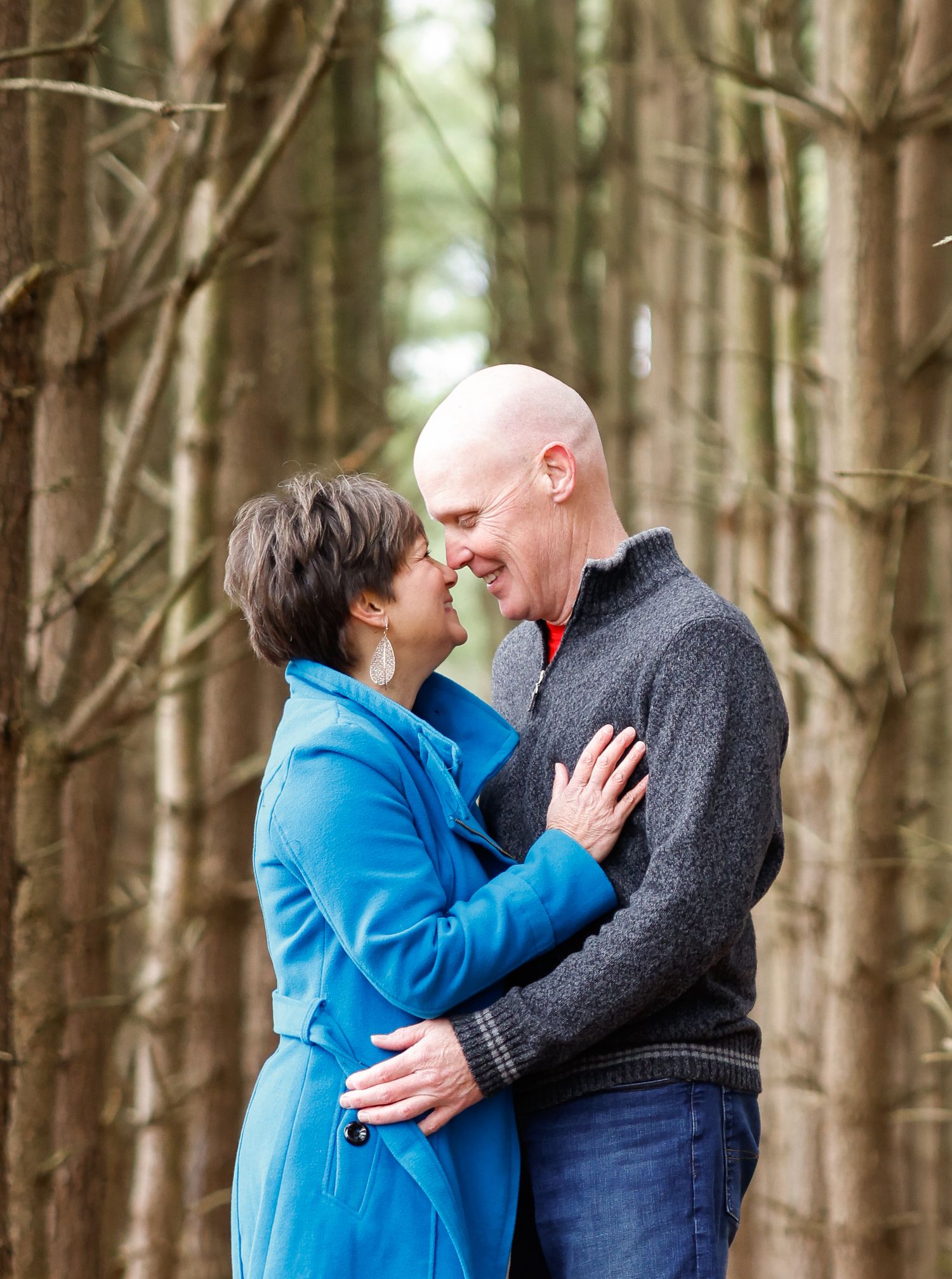 Intimate engagement photos of a couple embracing in a serene forest setting.