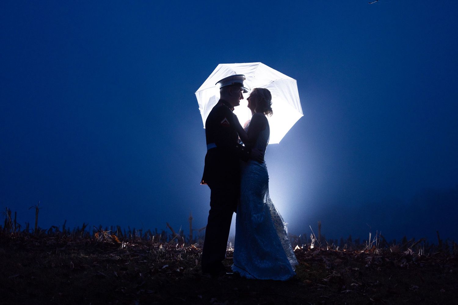 Silhouetted figures stand against a dramatic night sky with a bright glowing moon creating a romantic atmosphere.