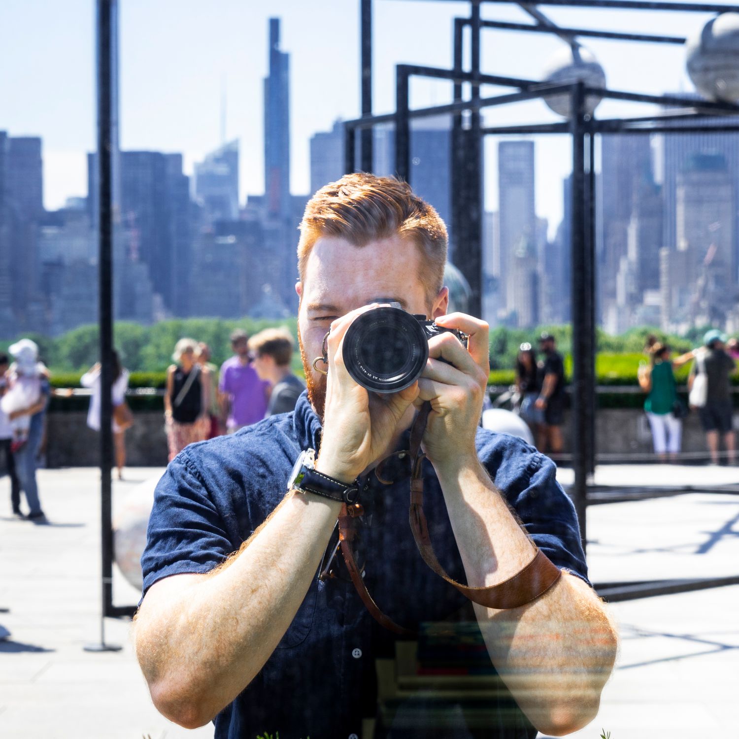 Nick Cunningham holding a camera with the New York City skyline reflected behind him