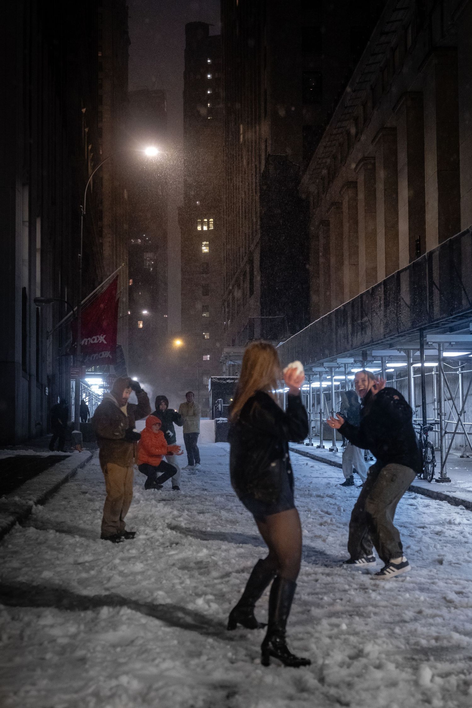 Friends having snowball fight on a snow-covered Wall Street at night.