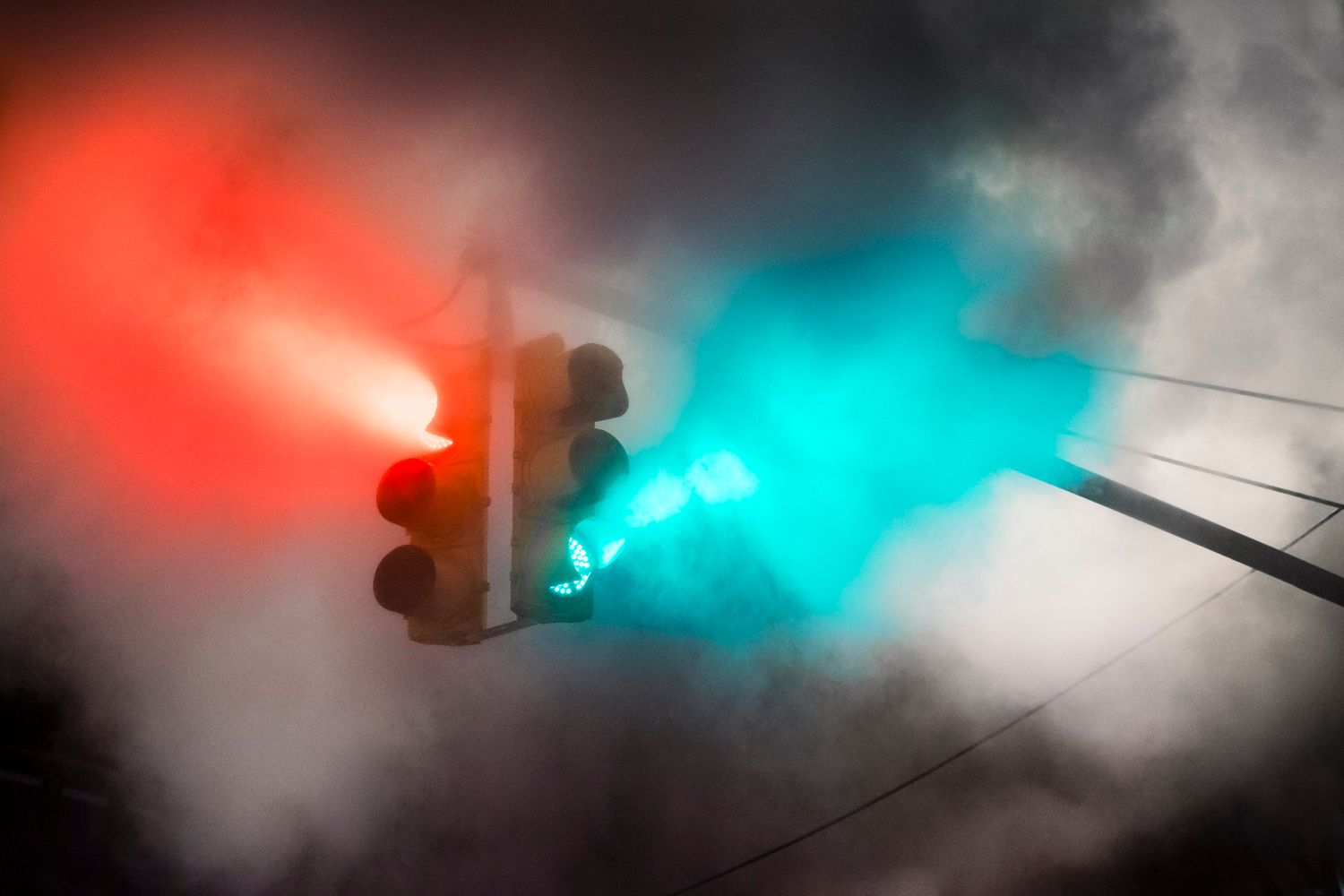 Red and green traffic lights glowing through thick clouds of steam