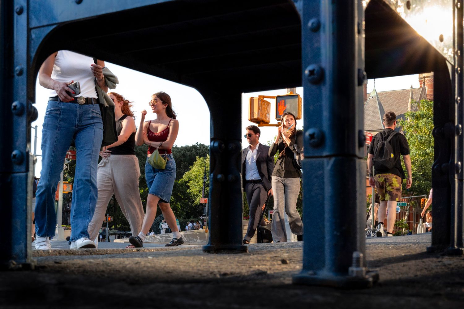 Pedestrians crossing paths on a New York City sidewalk framed through geometric openings
