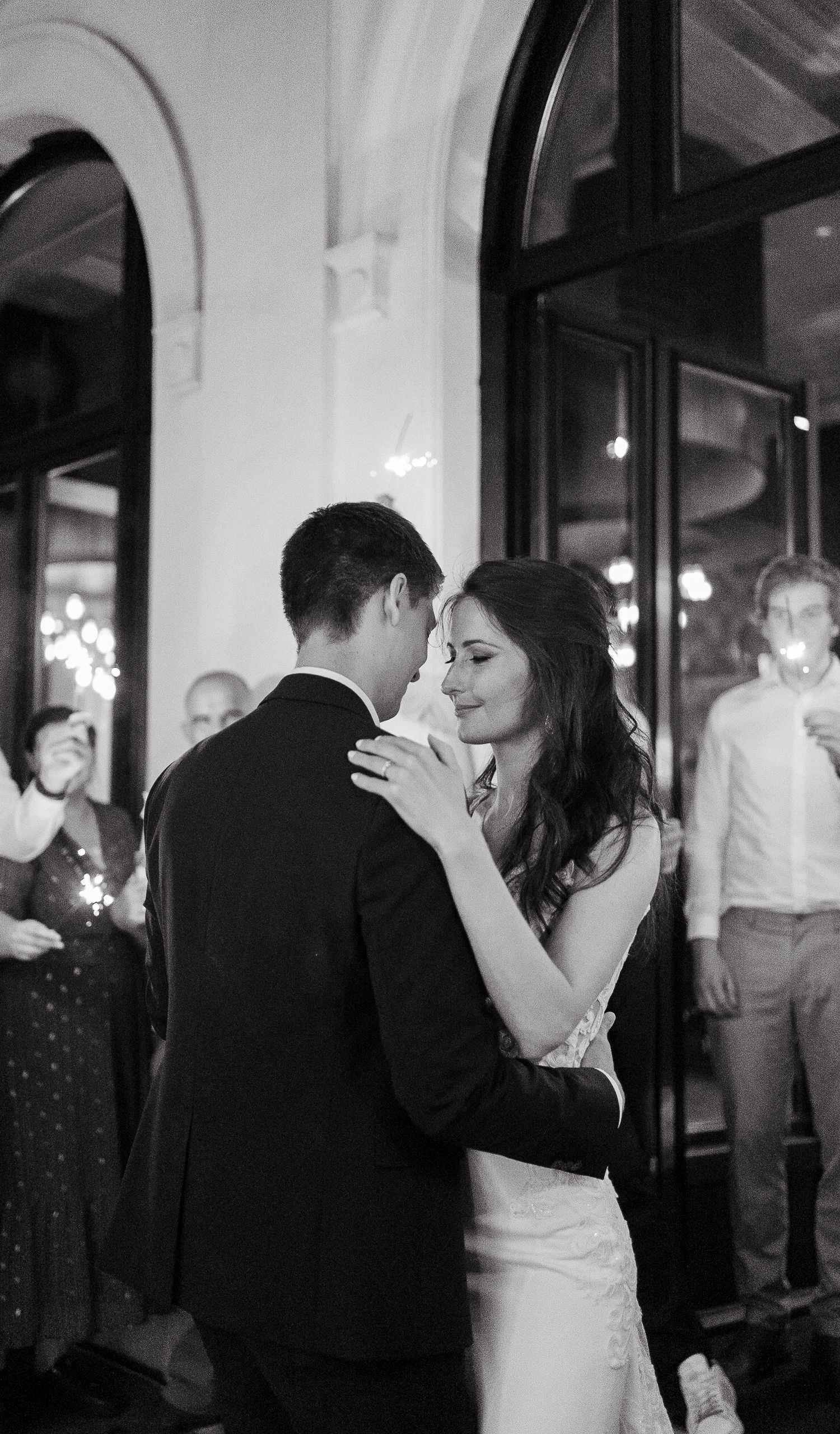 Black and white photo of a bride and groom sharing their first dance at a wedding reception.