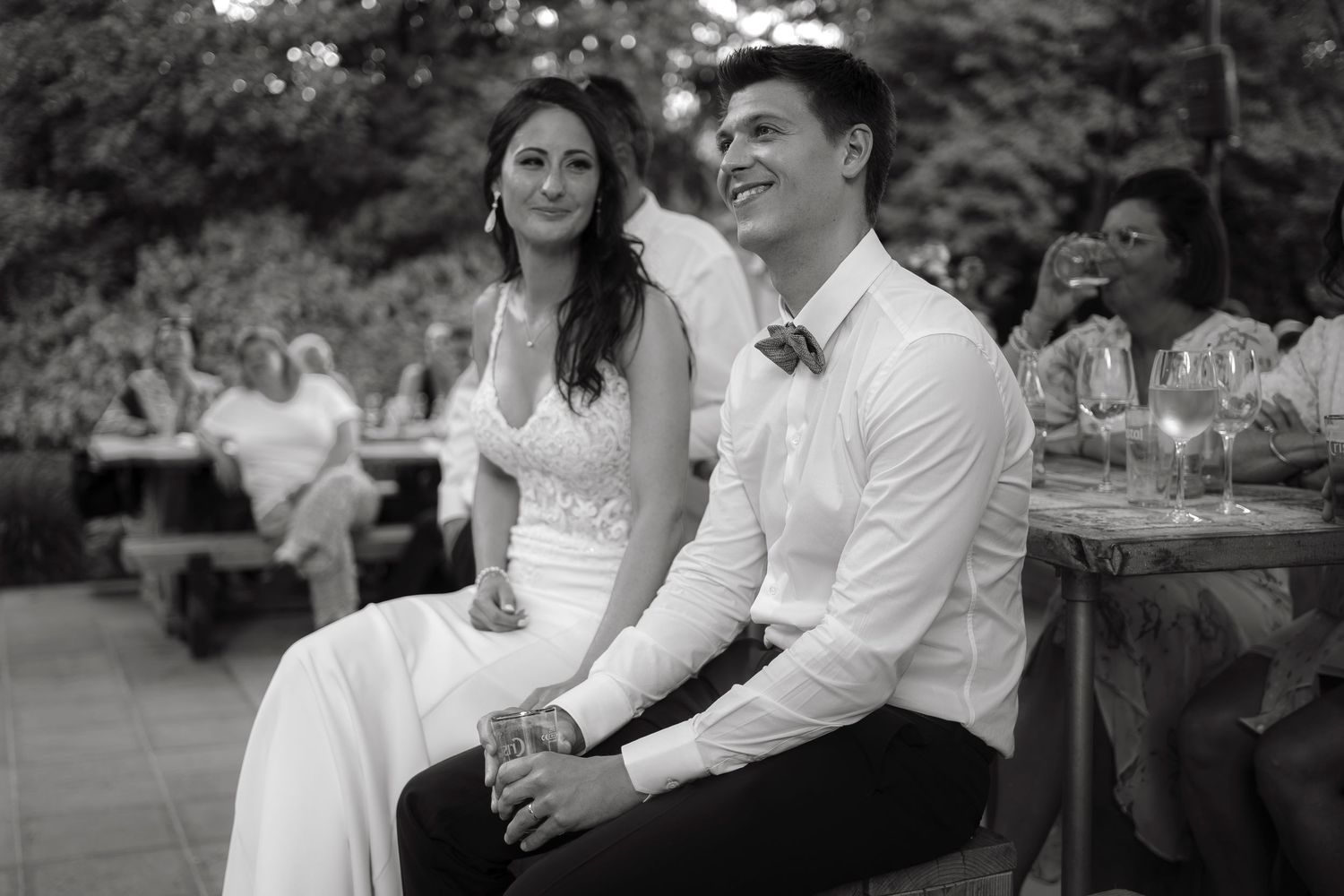 Black and white photo of a bride and groom smiling at their outdoor wedding reception.