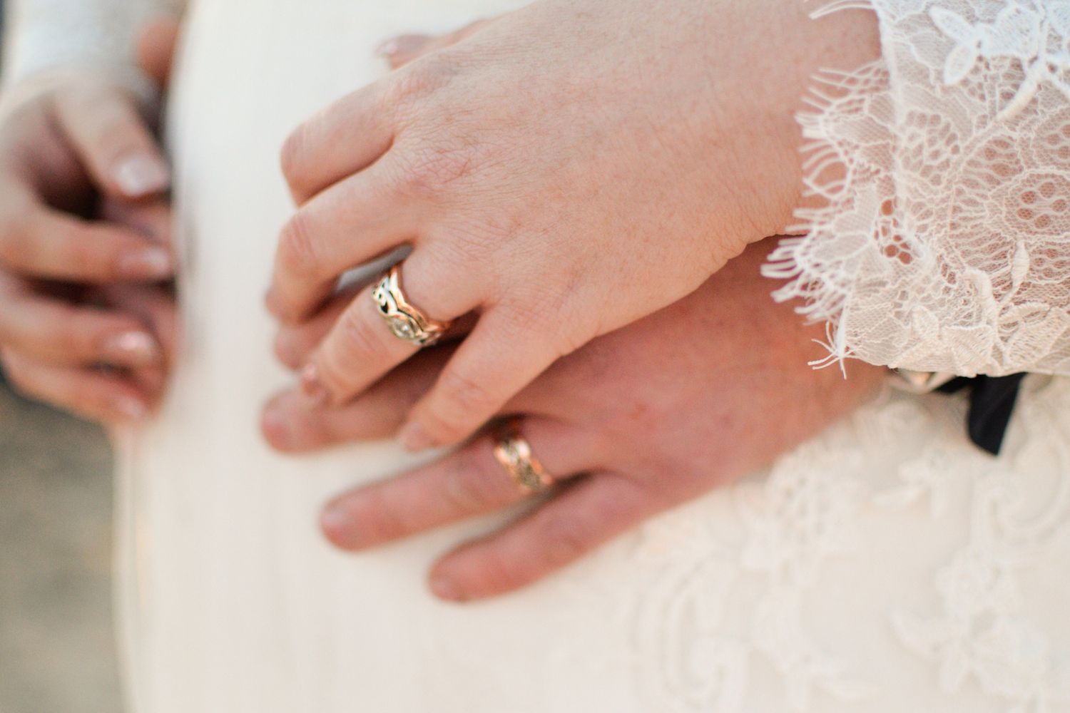 Close up view of hands exchanging wedding rings during a traditional ceremony with white lace details.